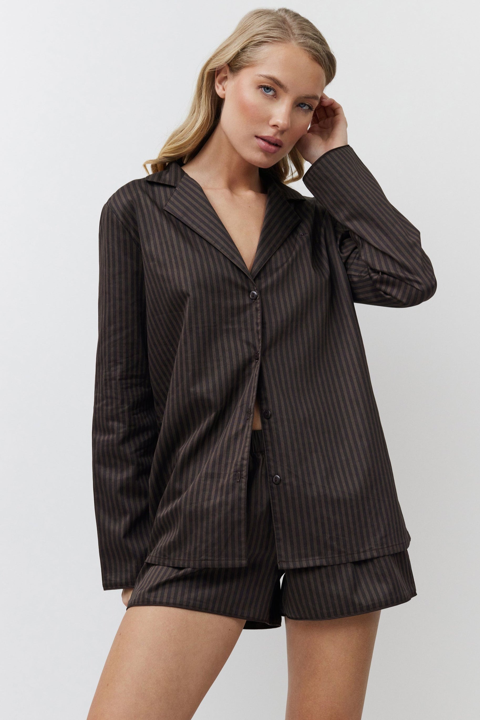 Woman wearing a brown pajama set against a white background