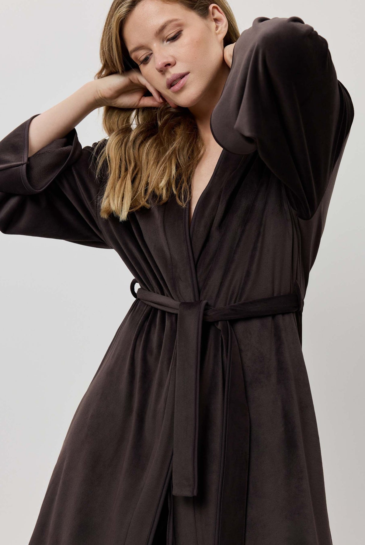Woman wearing a dark brown robe against a plain background