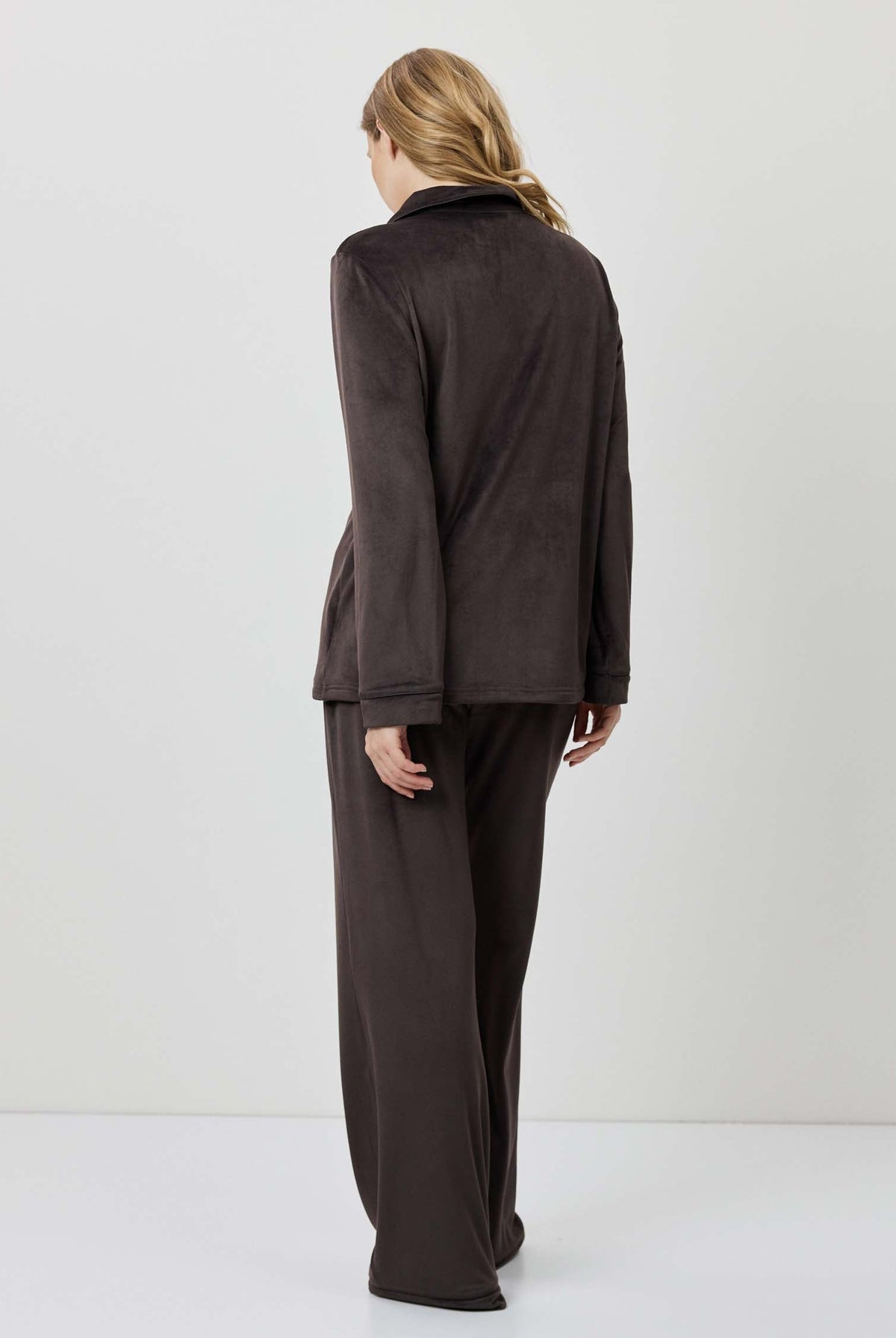 Person wearing a brown outfit standing against a white background