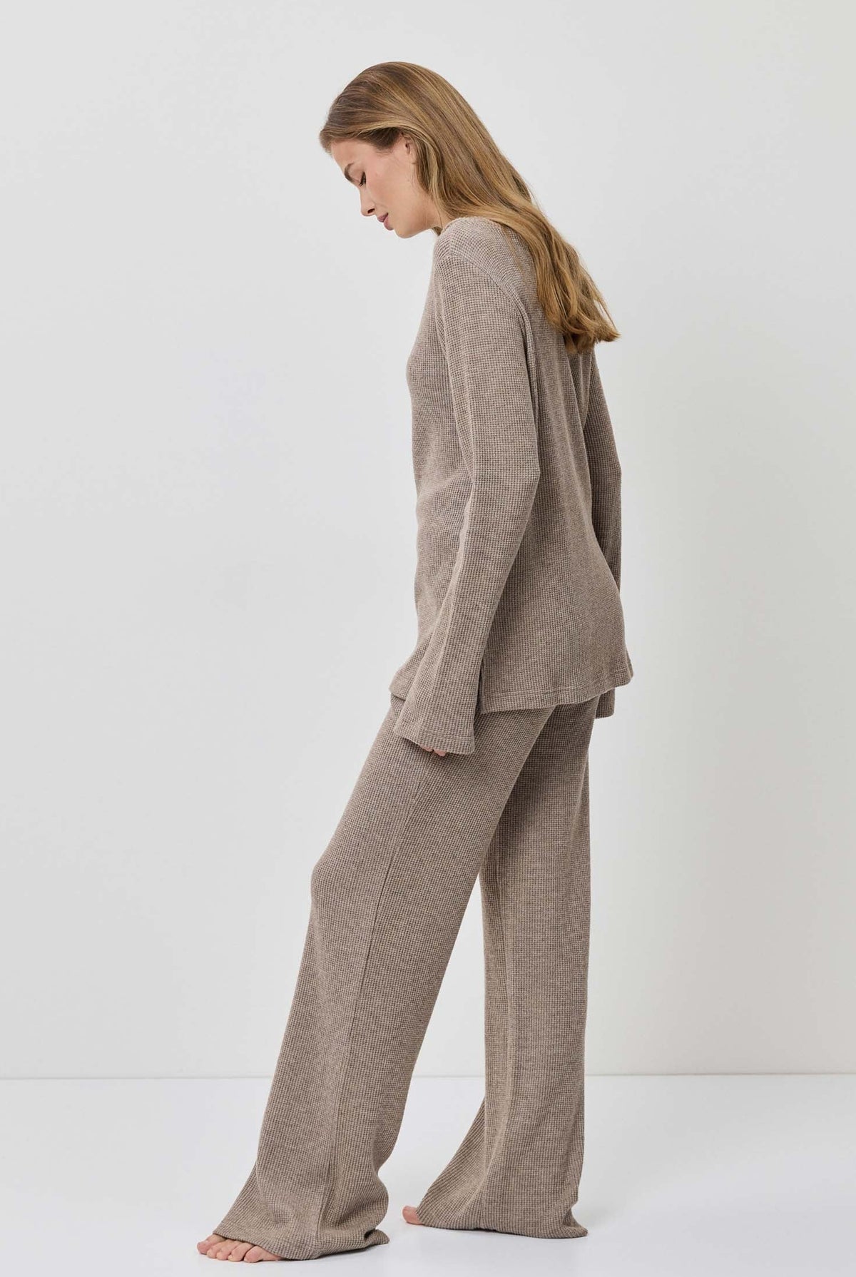 Woman wearing a beige suit standing against a white background