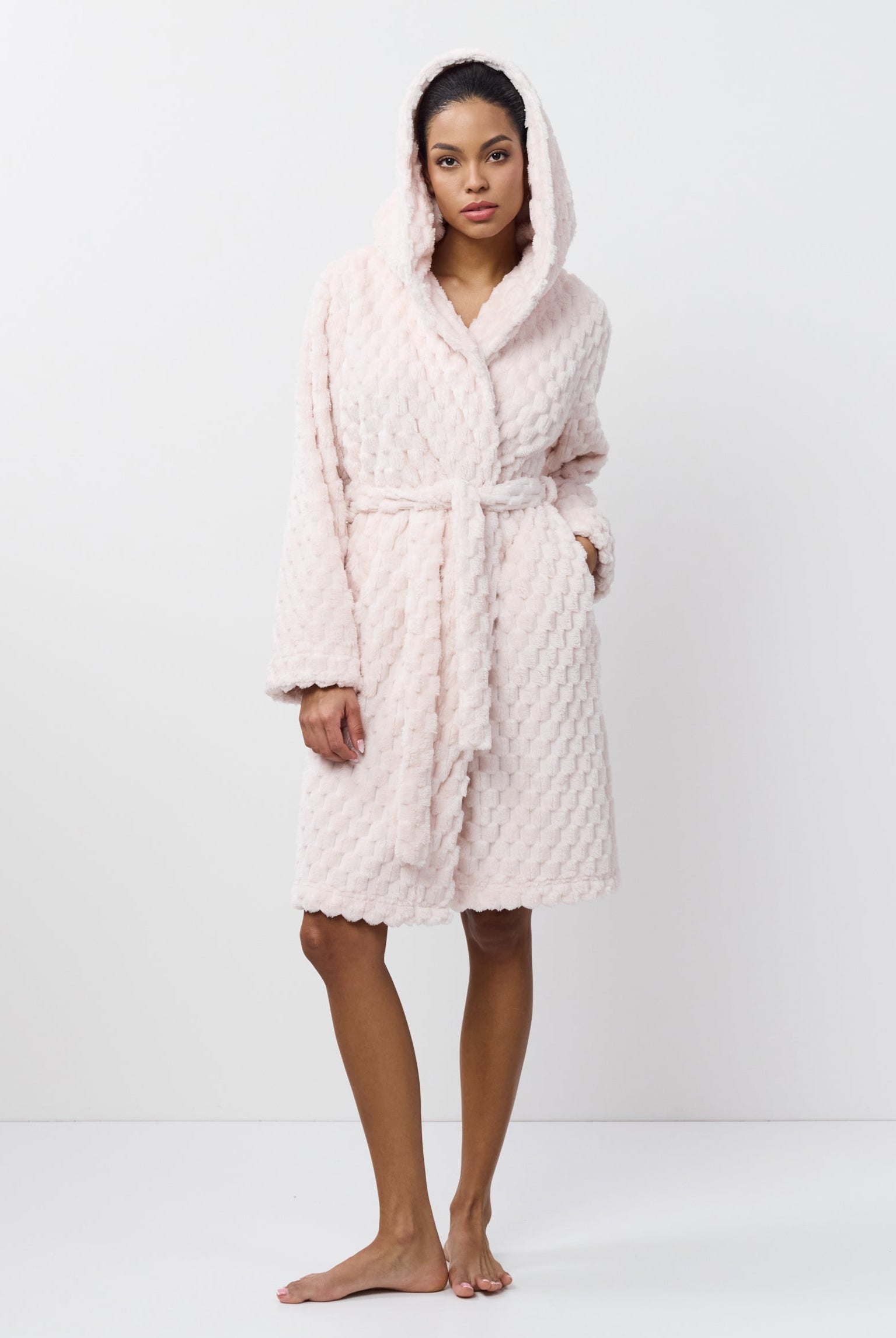 Person wearing a textured pink bathrobe on a white background