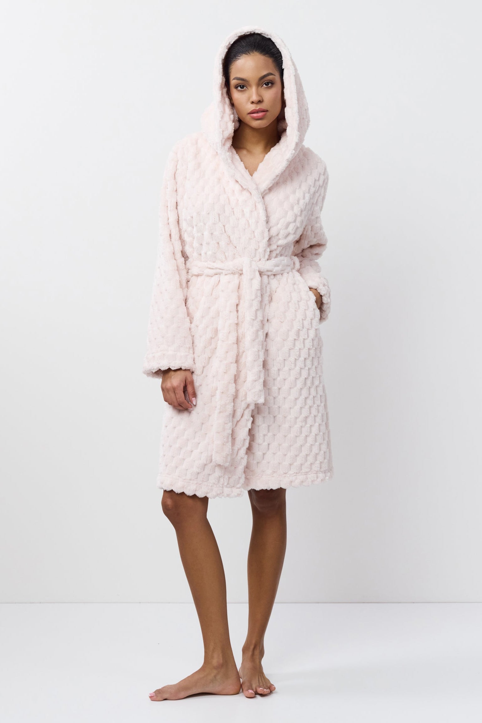 Person wearing a textured pink bathrobe on a white background