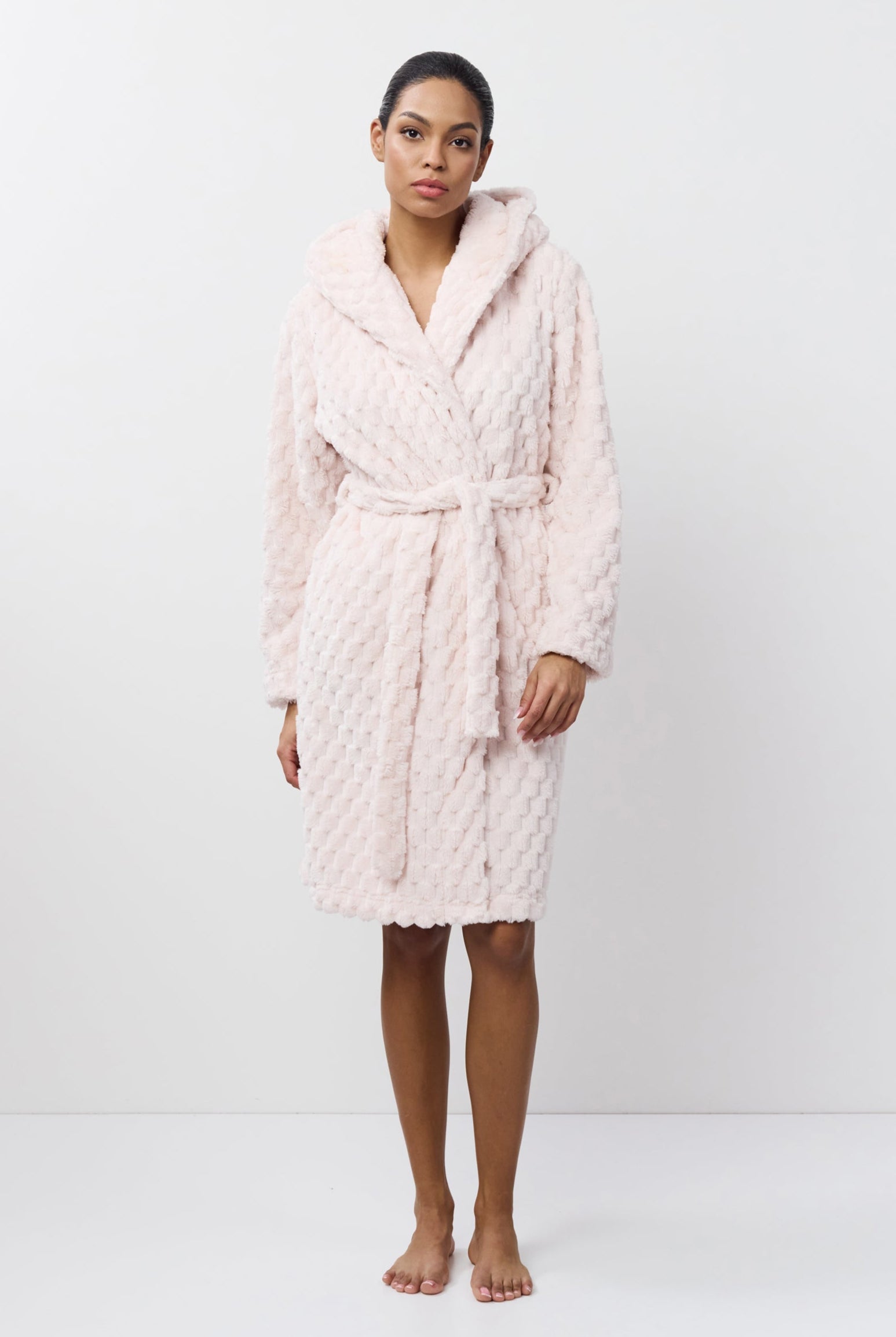 Person wearing a pink quilted bathrobe on a white background