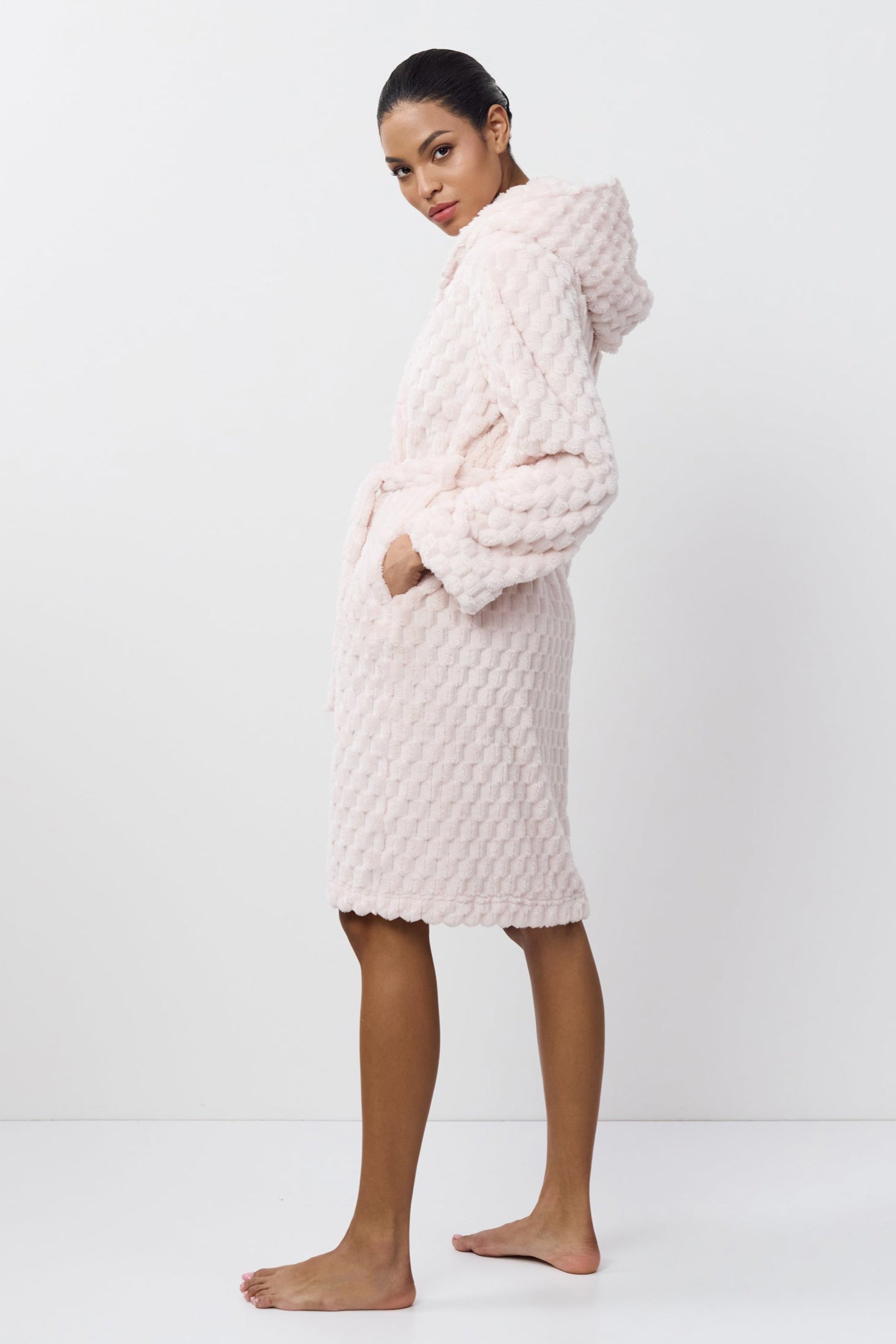 Person wearing a textured pink bathrobe on a white background