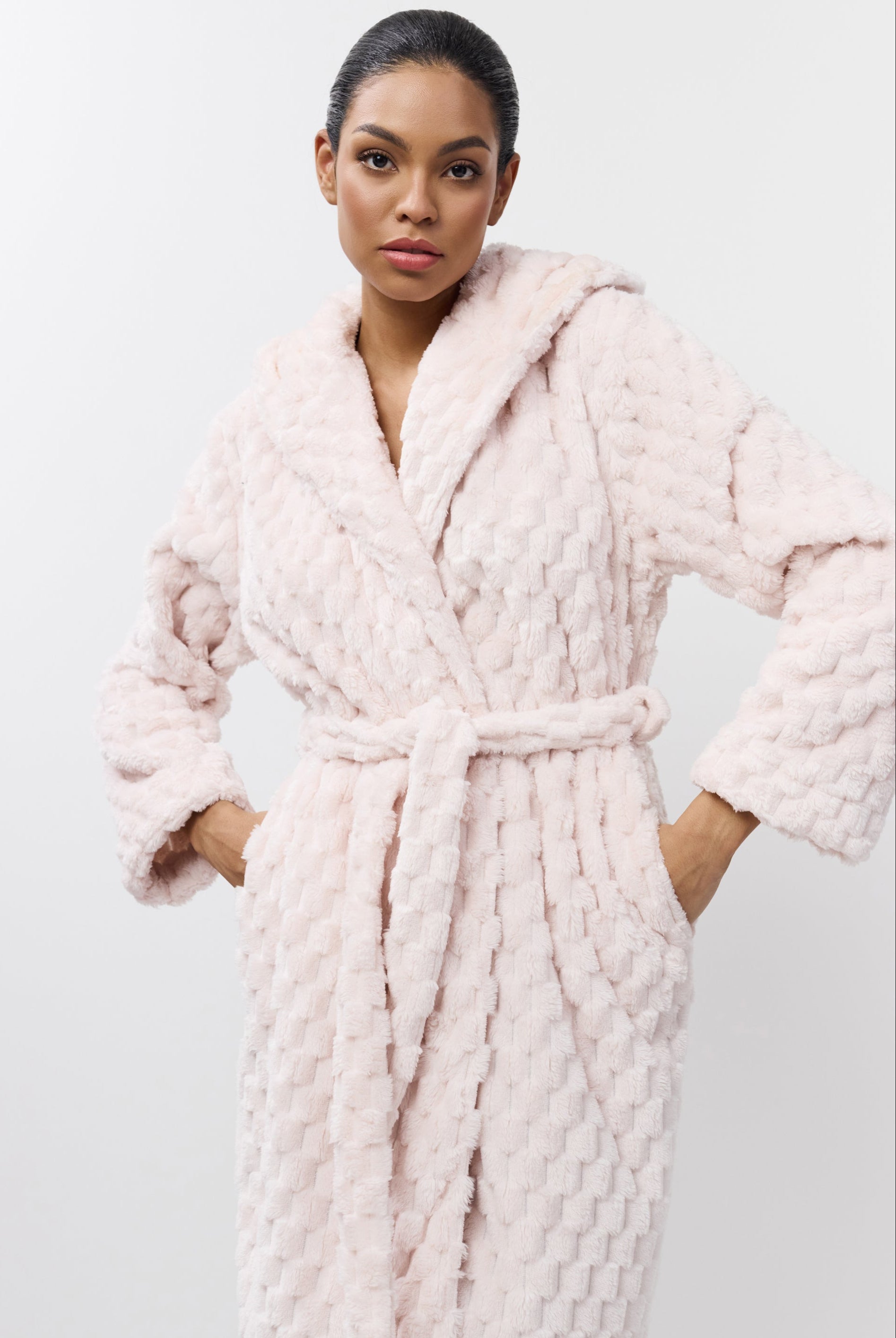 Woman wearing a pink textured bathrobe against a white background