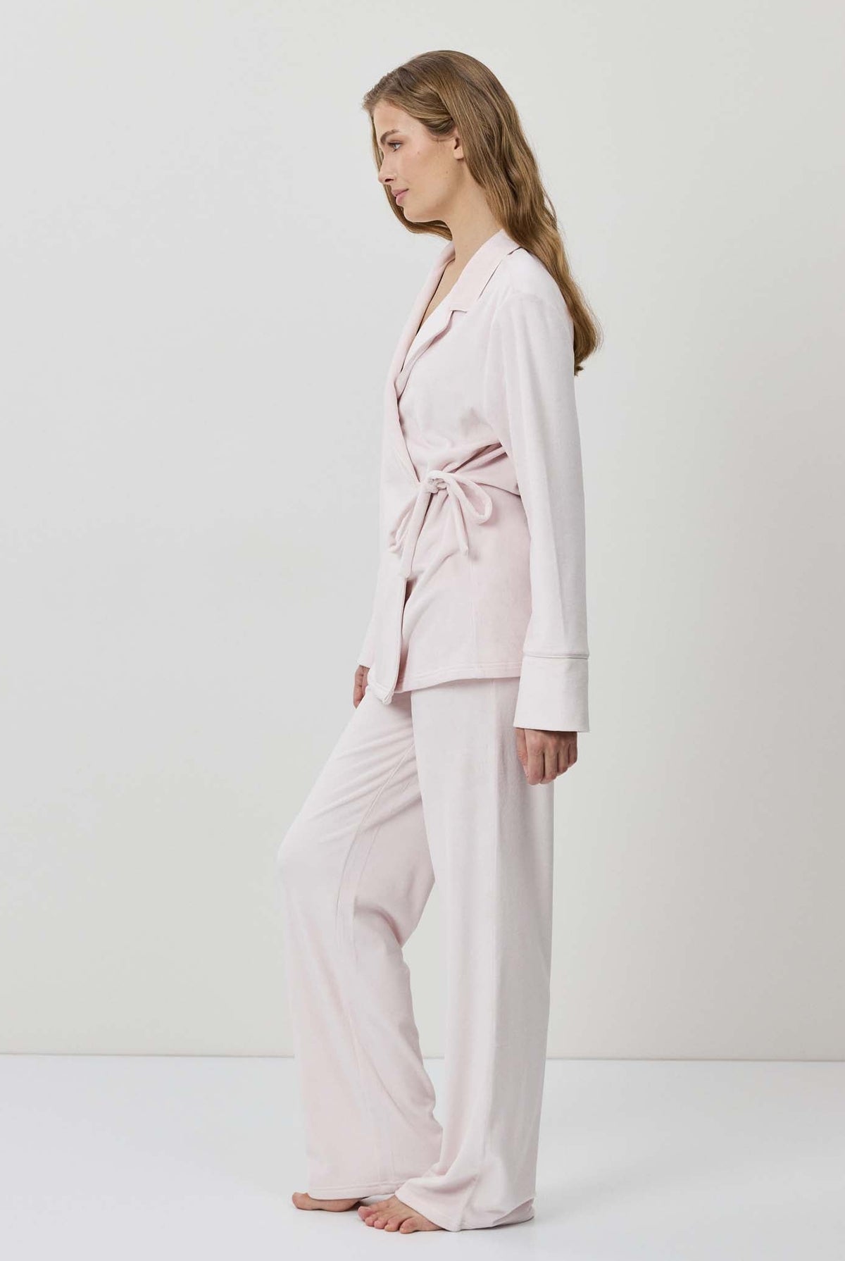 Woman wearing a light pink pajama set on a white background