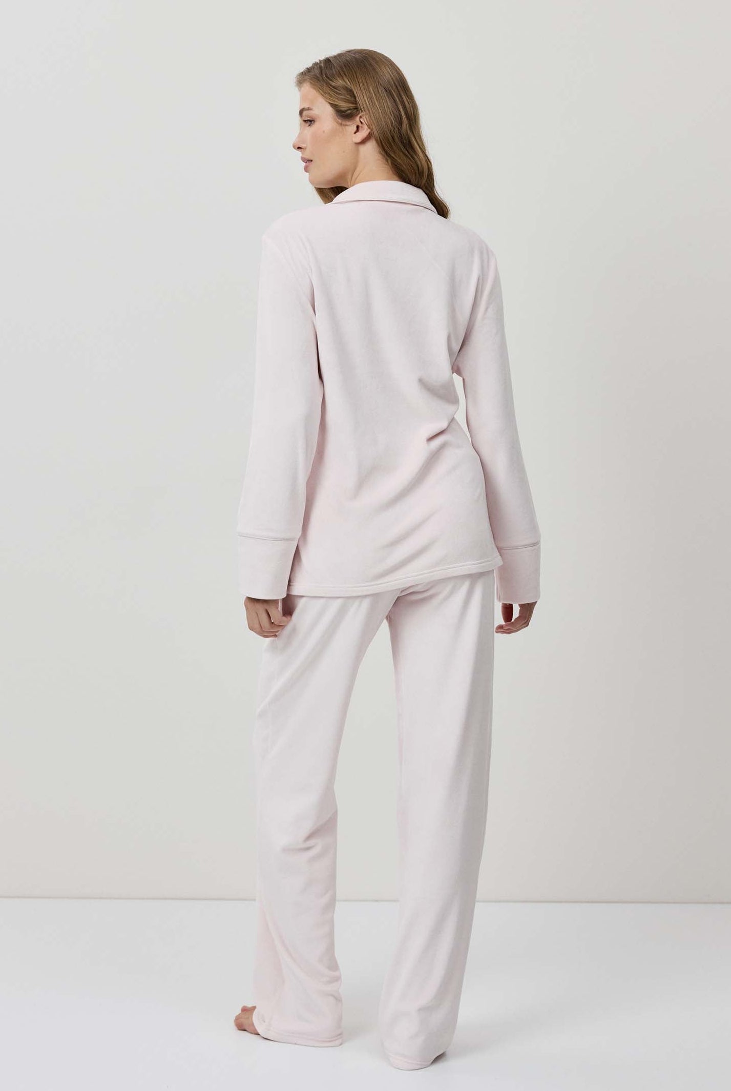 Woman wearing a light pink pajama set against a white background