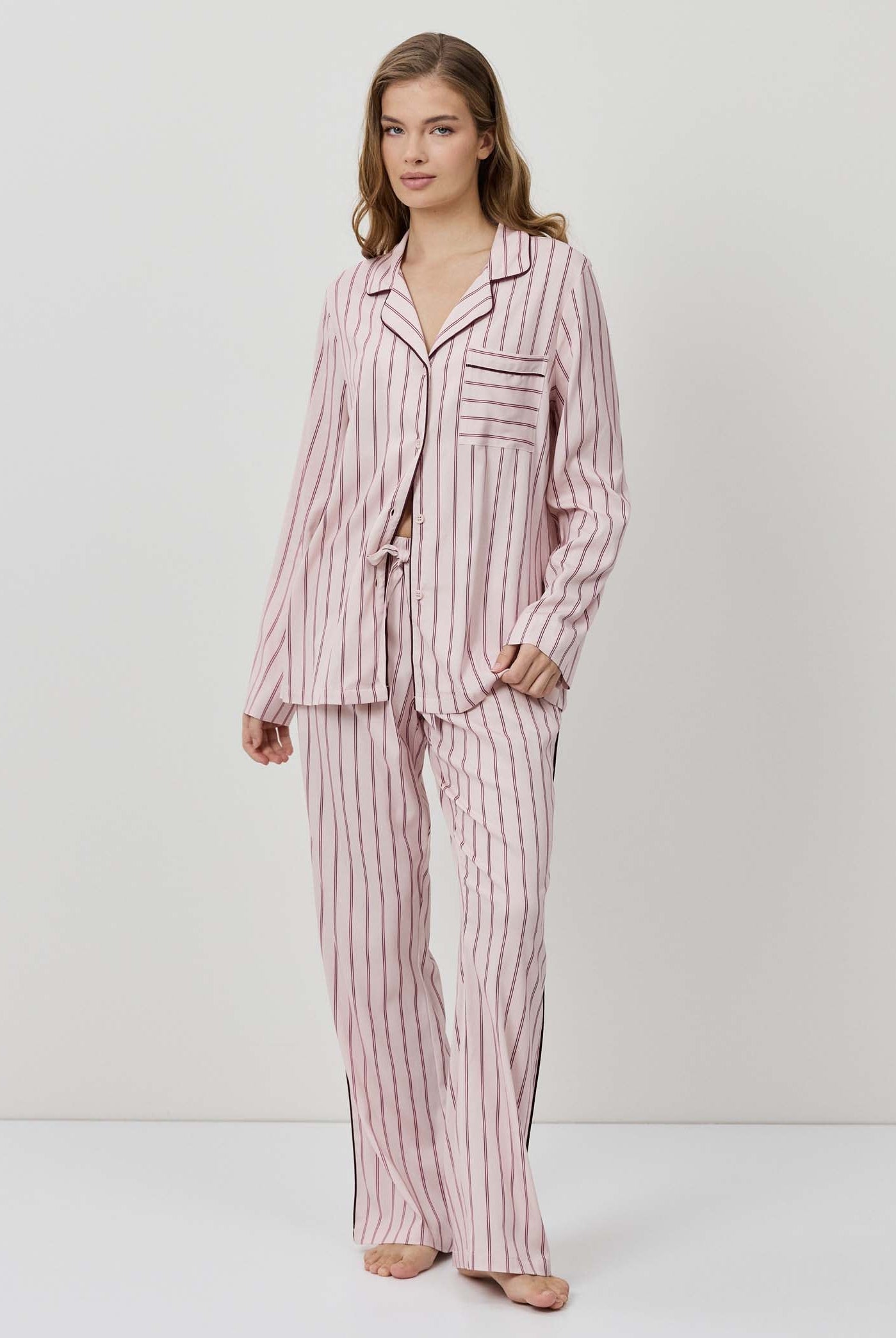 Woman wearing a pink and white striped pajama set on a white background