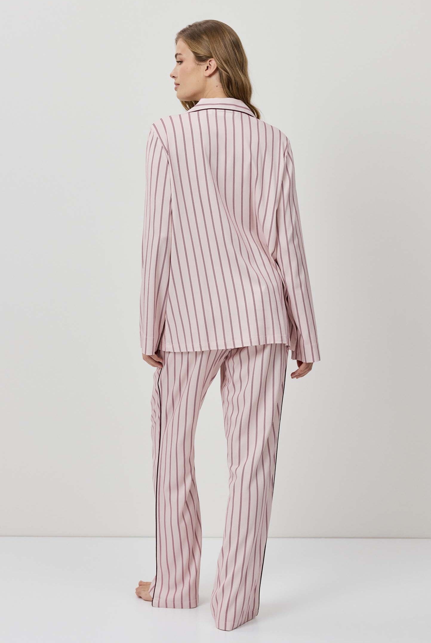 Woman wearing a pink and white striped pajama set on a white background