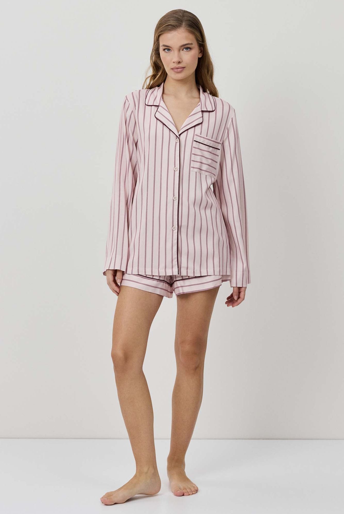 Woman wearing a pink striped pajama set on a white background