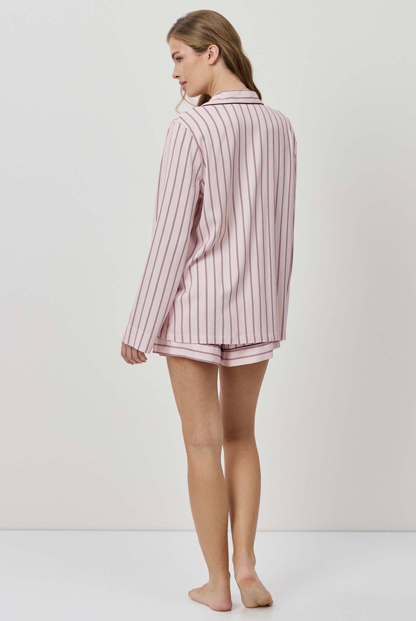 Woman wearing a pink striped pajama set on a white background