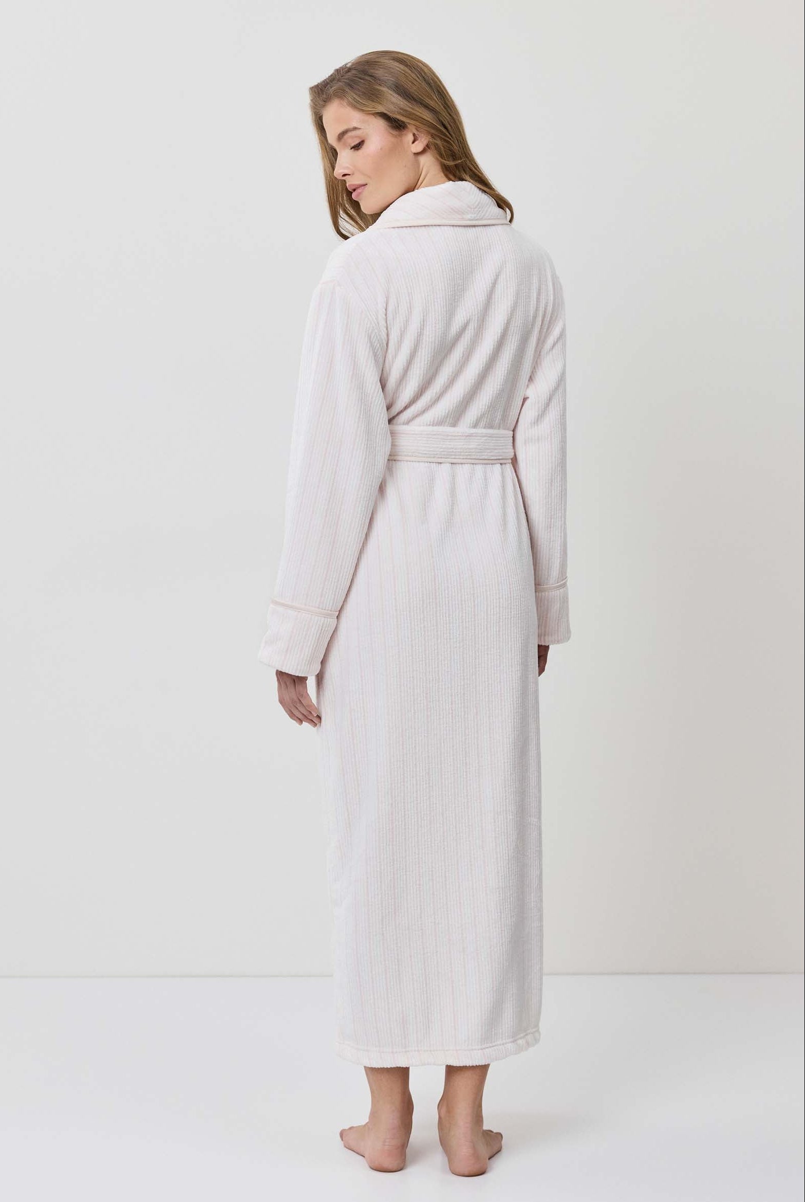 Woman wearing a white robe against a plain background