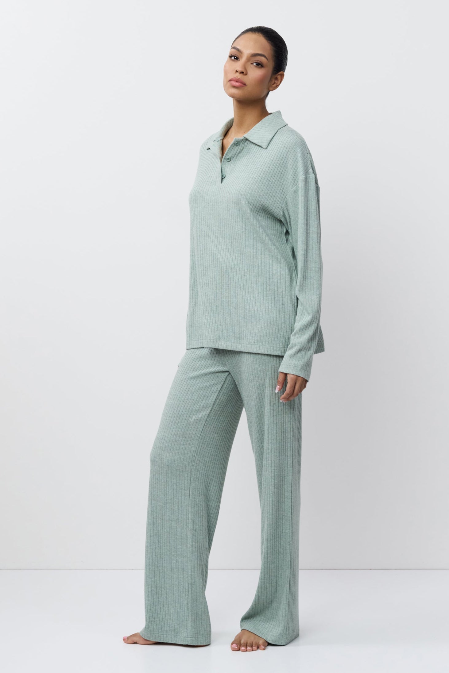 Woman wearing a light green pajama set against a white background