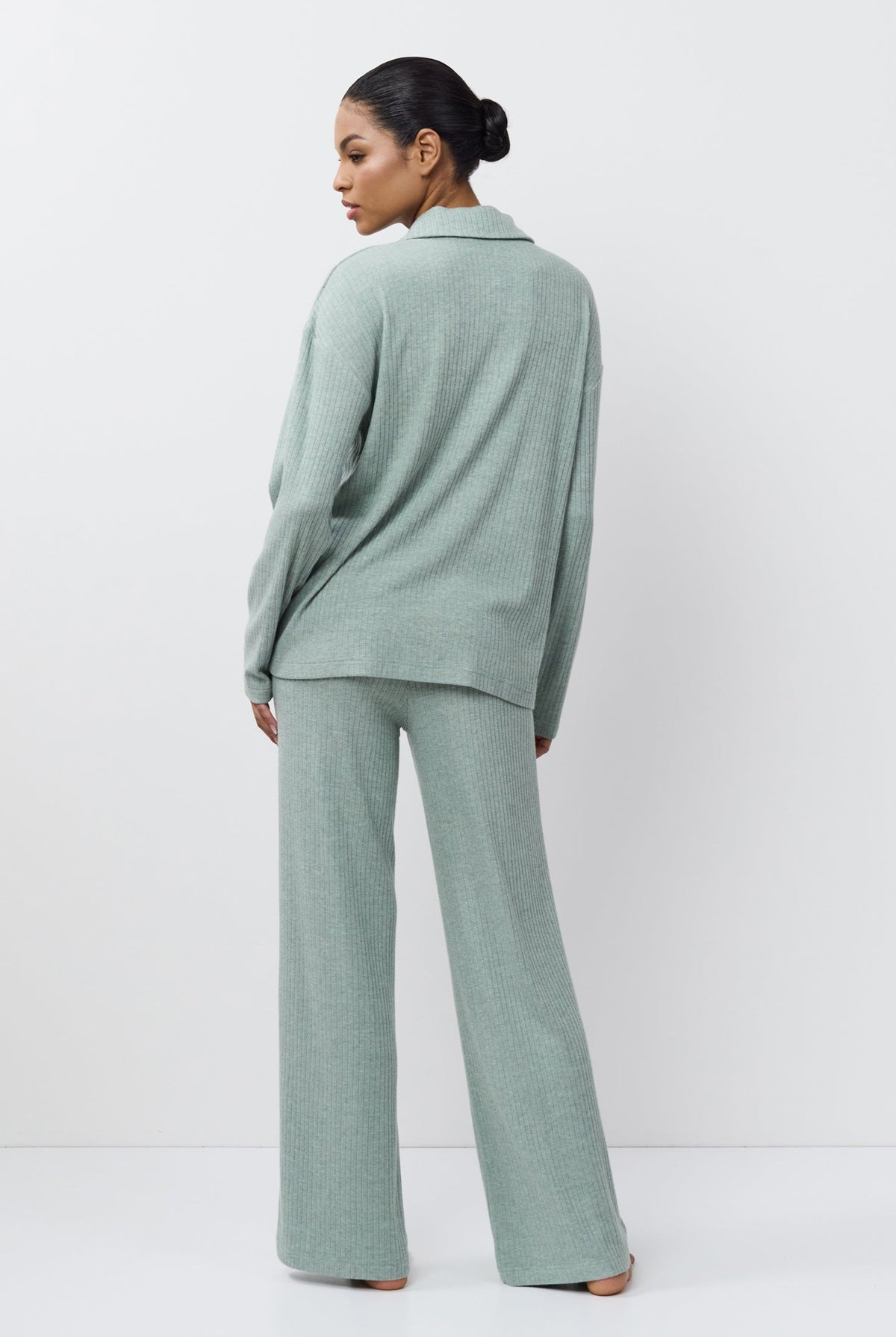 Person wearing a light green outfit standing against a white background
