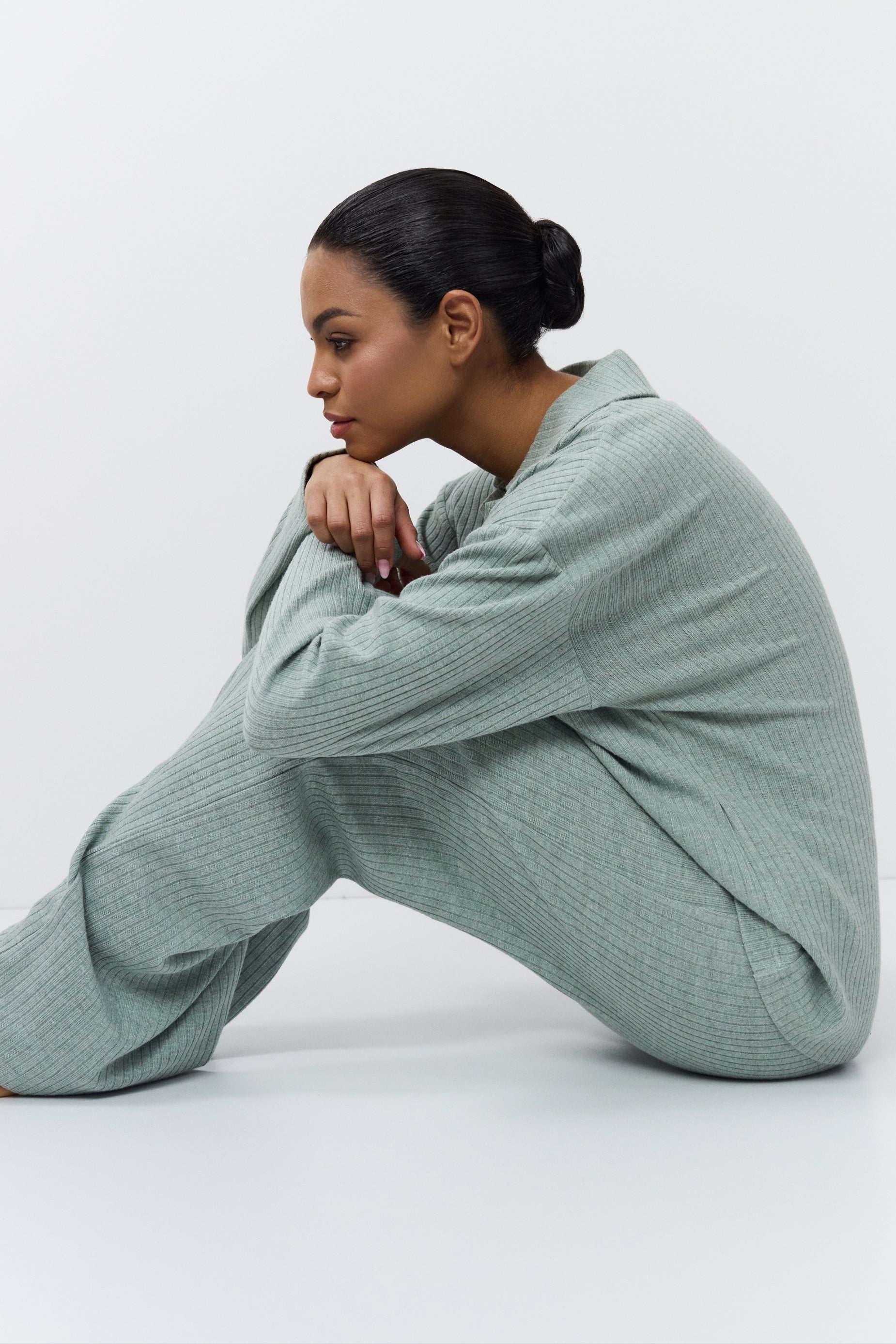 Woman wearing a light green outfit sitting on a white background