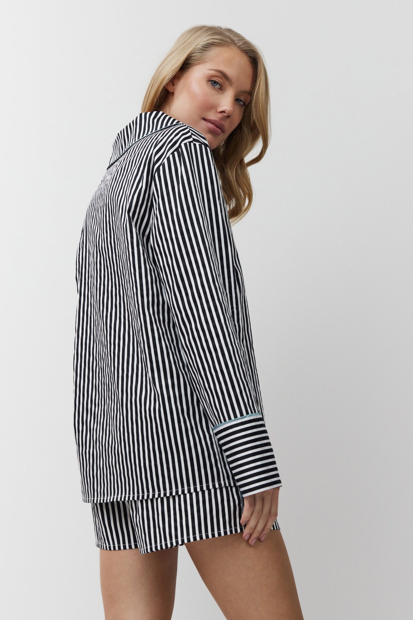 Woman wearing a black and white striped shirt dress on a plain background