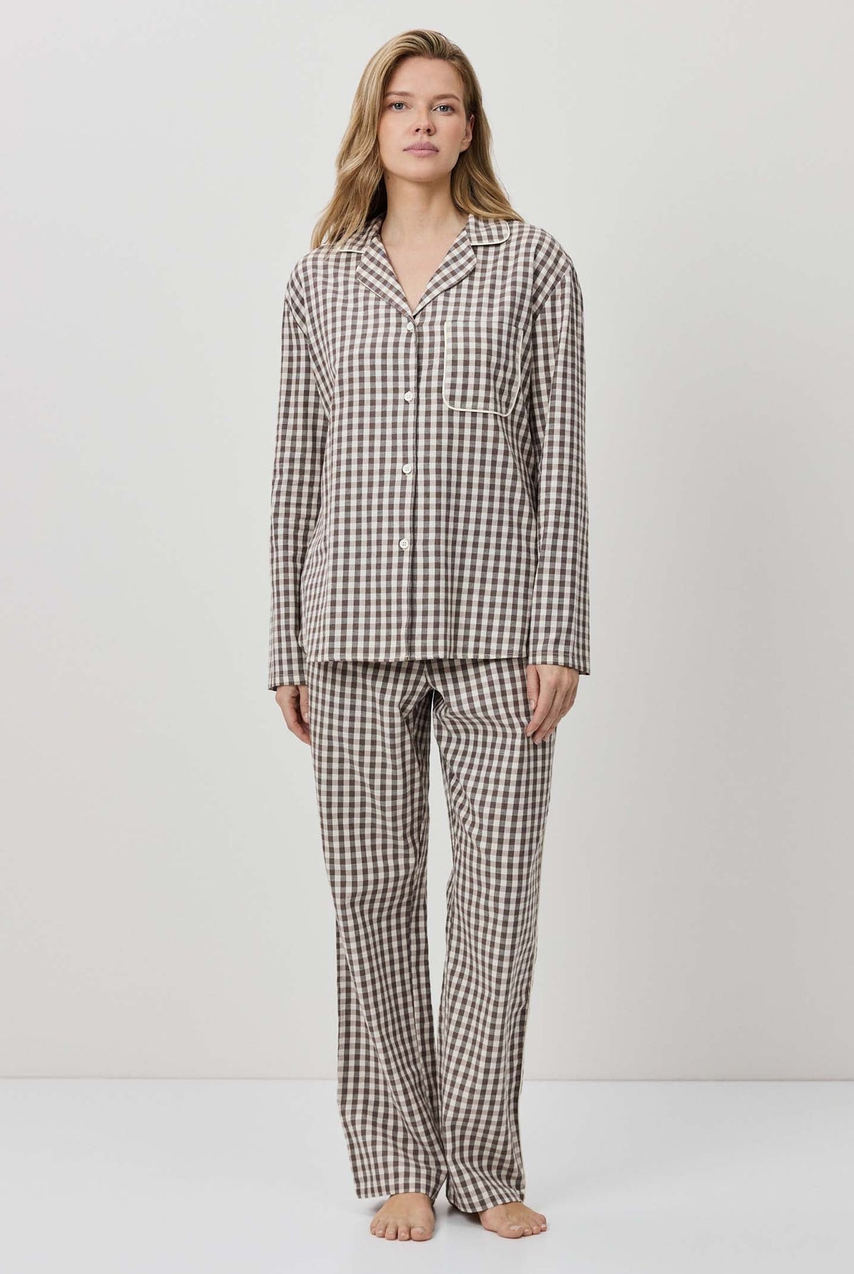 Woman wearing a checkered pajama set against a white background