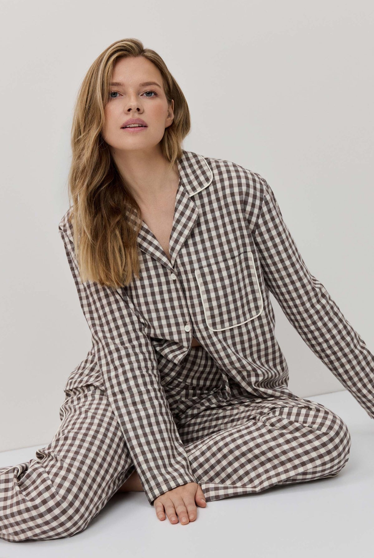 Woman wearing a checkered pajama set on a plain background