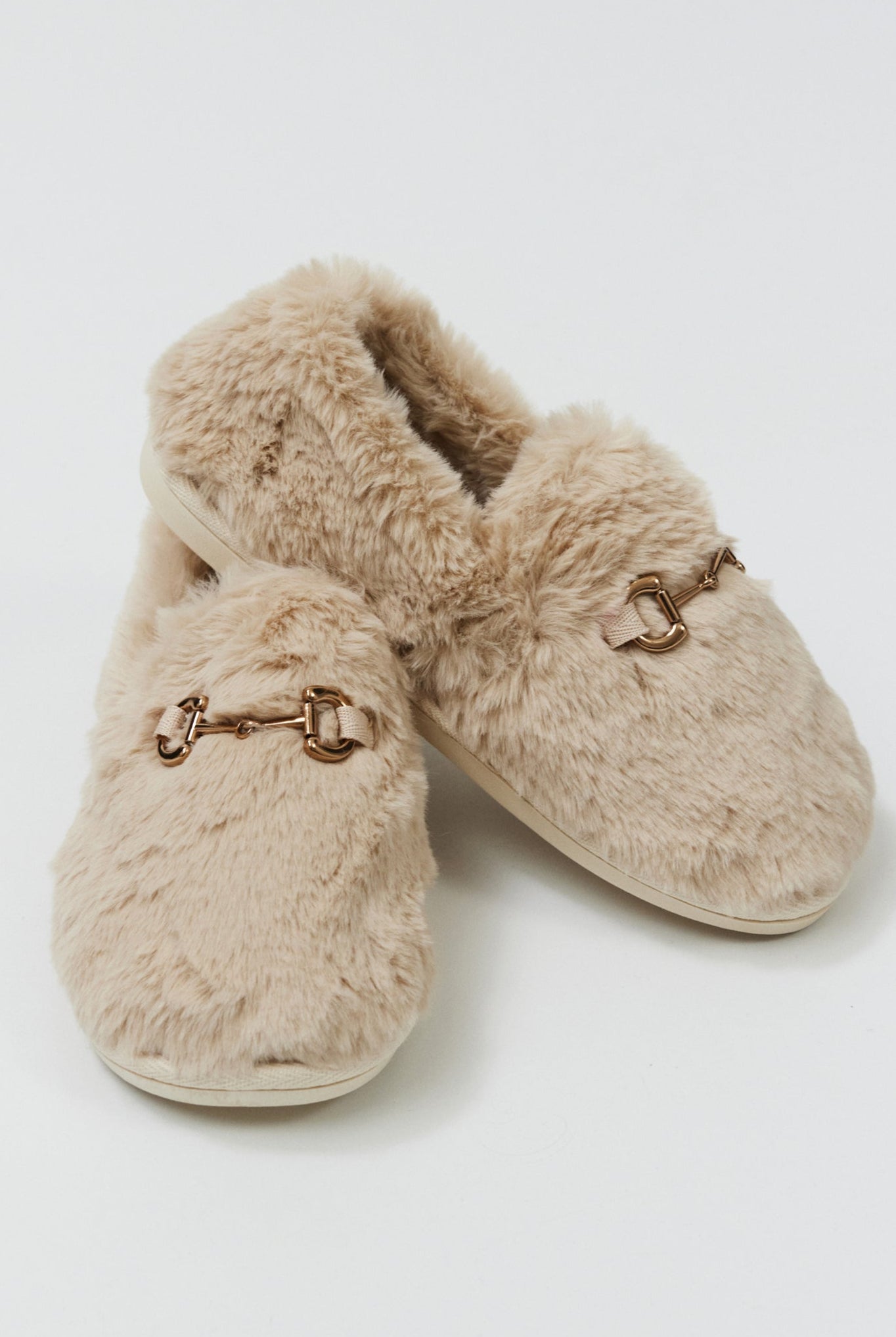 Pair of beige slippers with fur lining on a white background