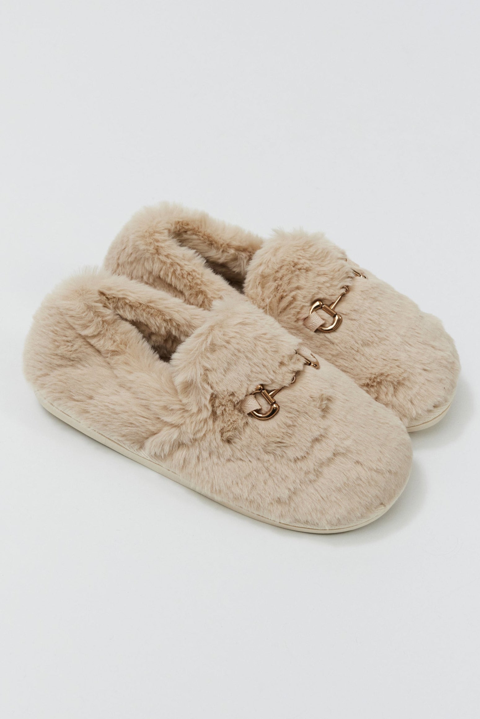 Pair of beige slippers with fluffy texture on a light gray background