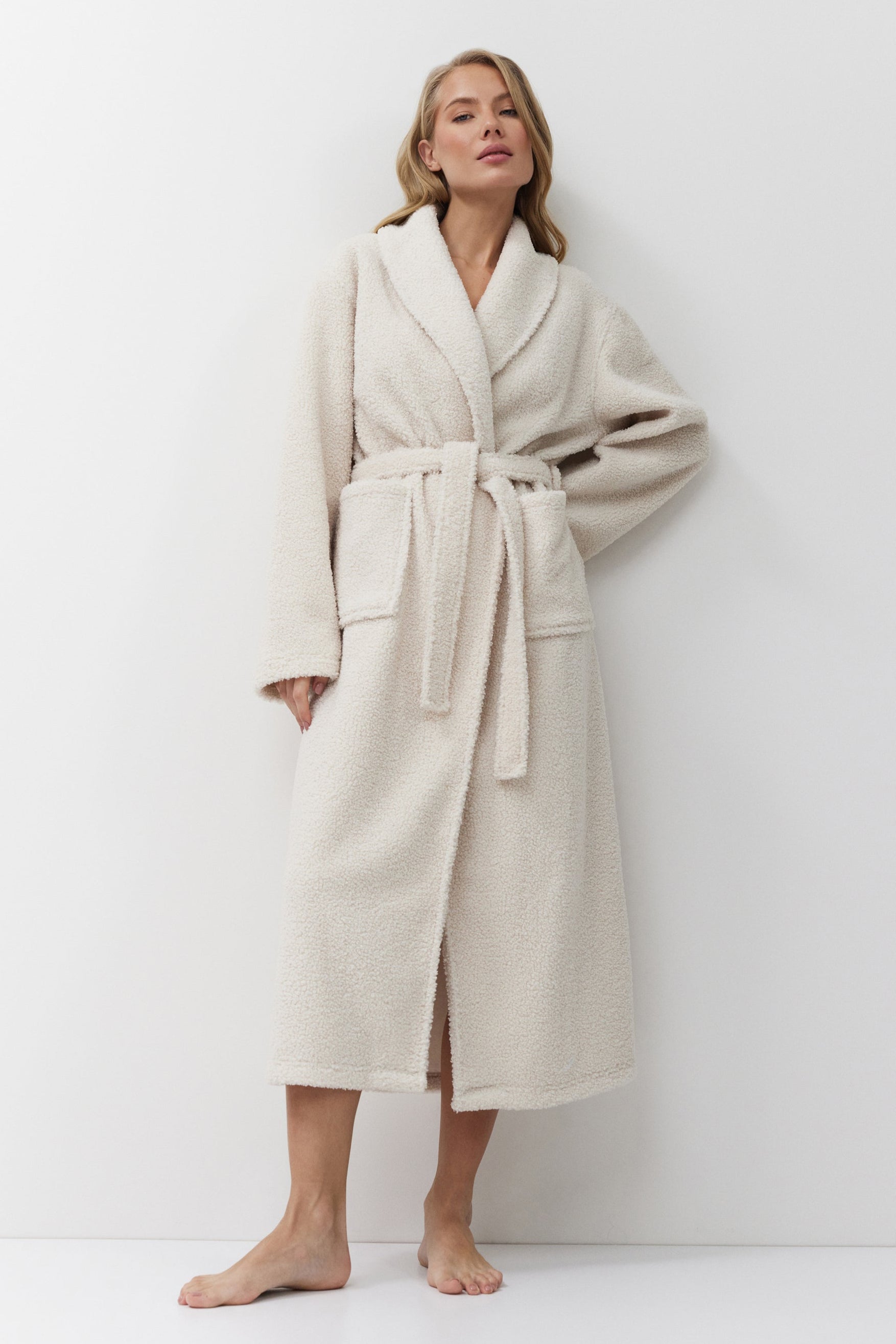 Woman wearing a beige bathrobe against a white background