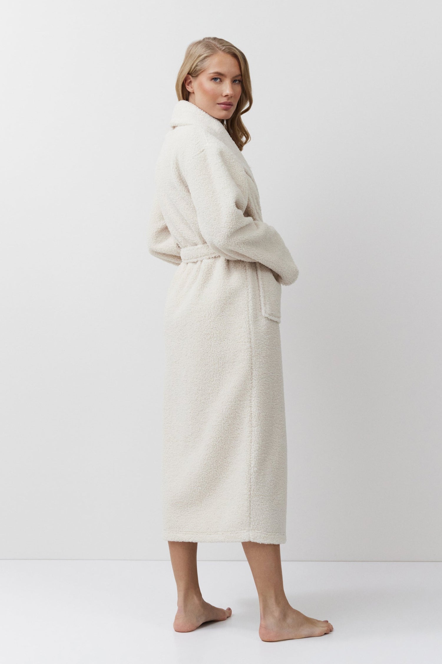 Woman wearing a beige bathrobe against a white background