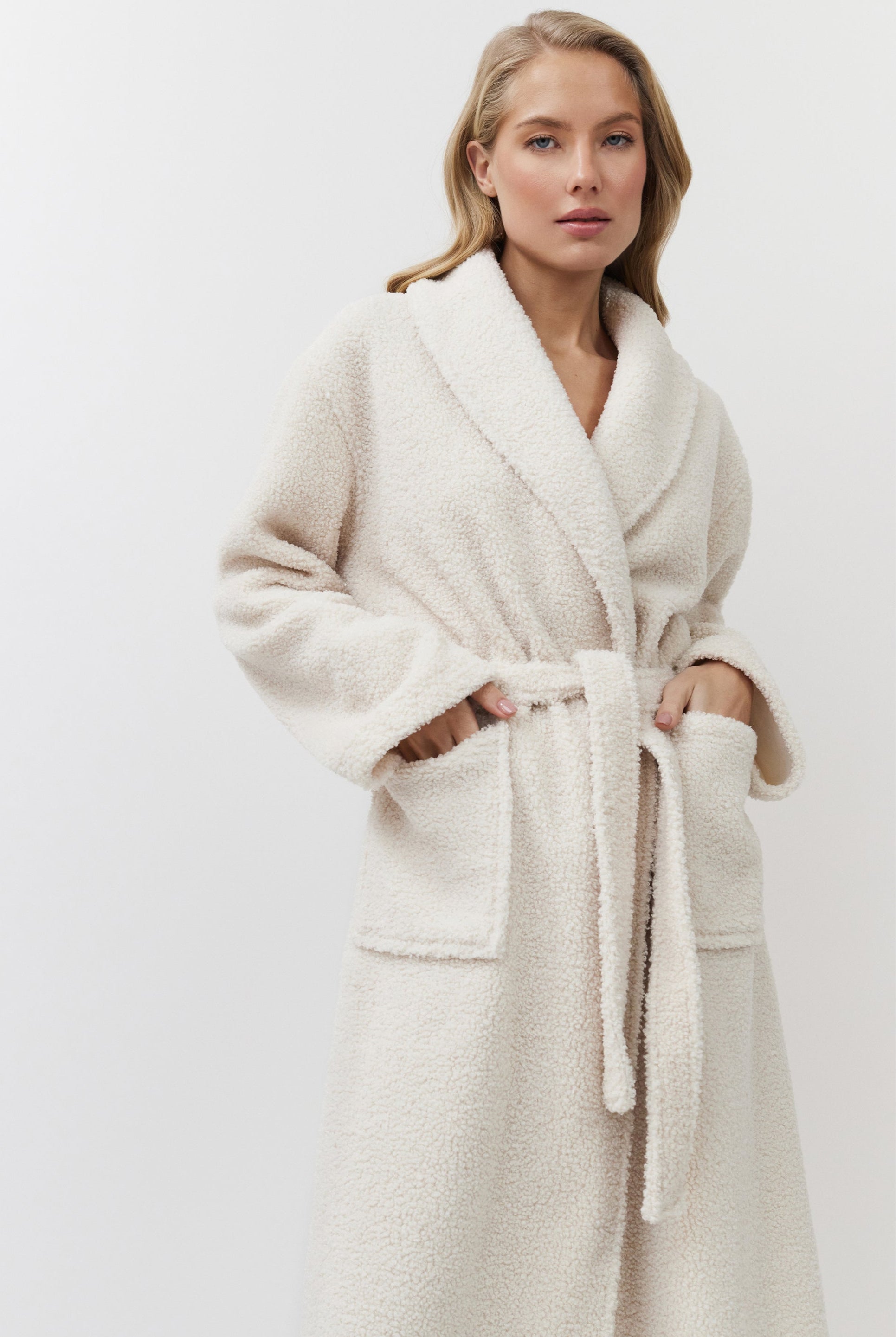 Woman wearing a cream-colored robe against a white background