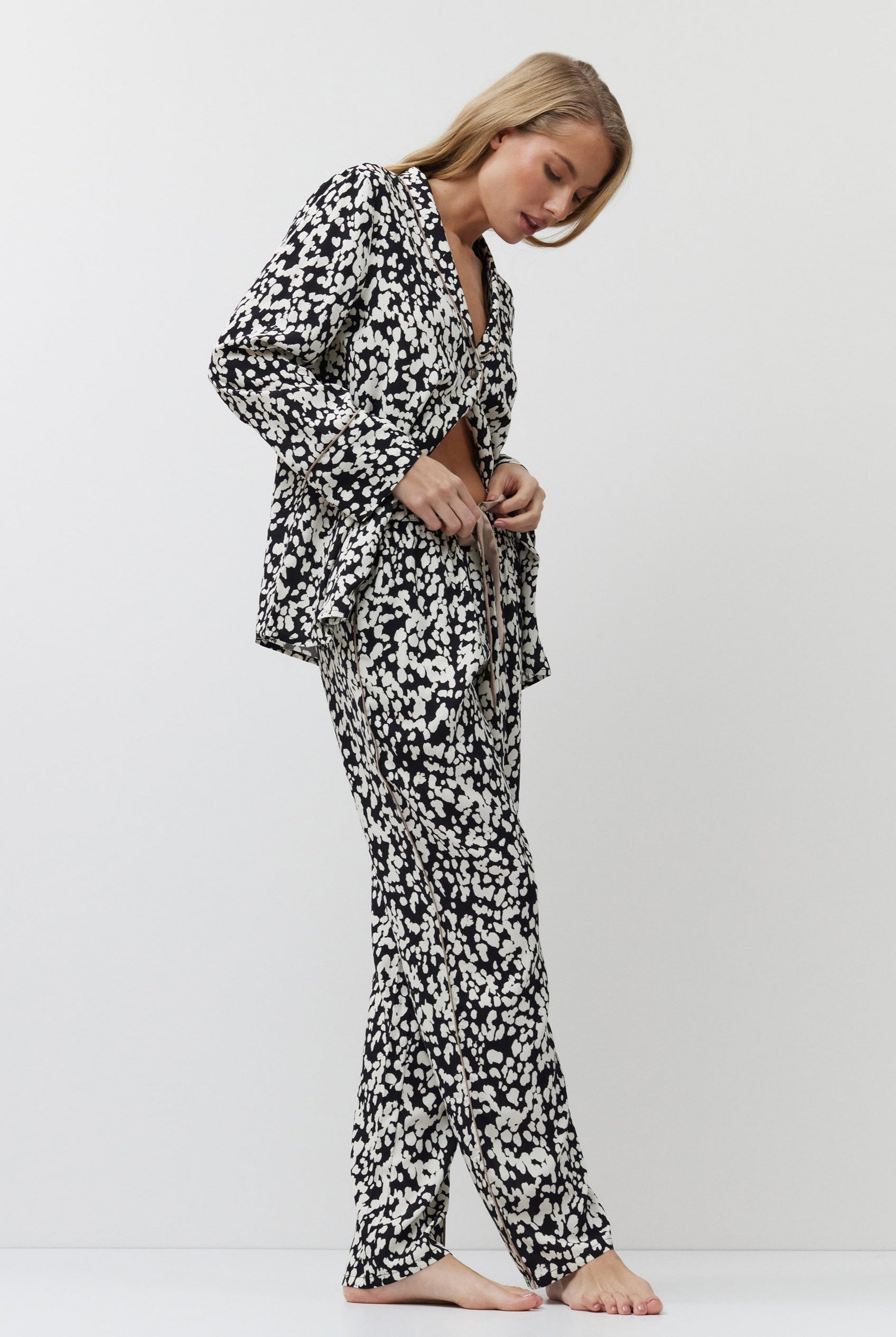 Woman wearing a black and white patterned pajama set on a white background