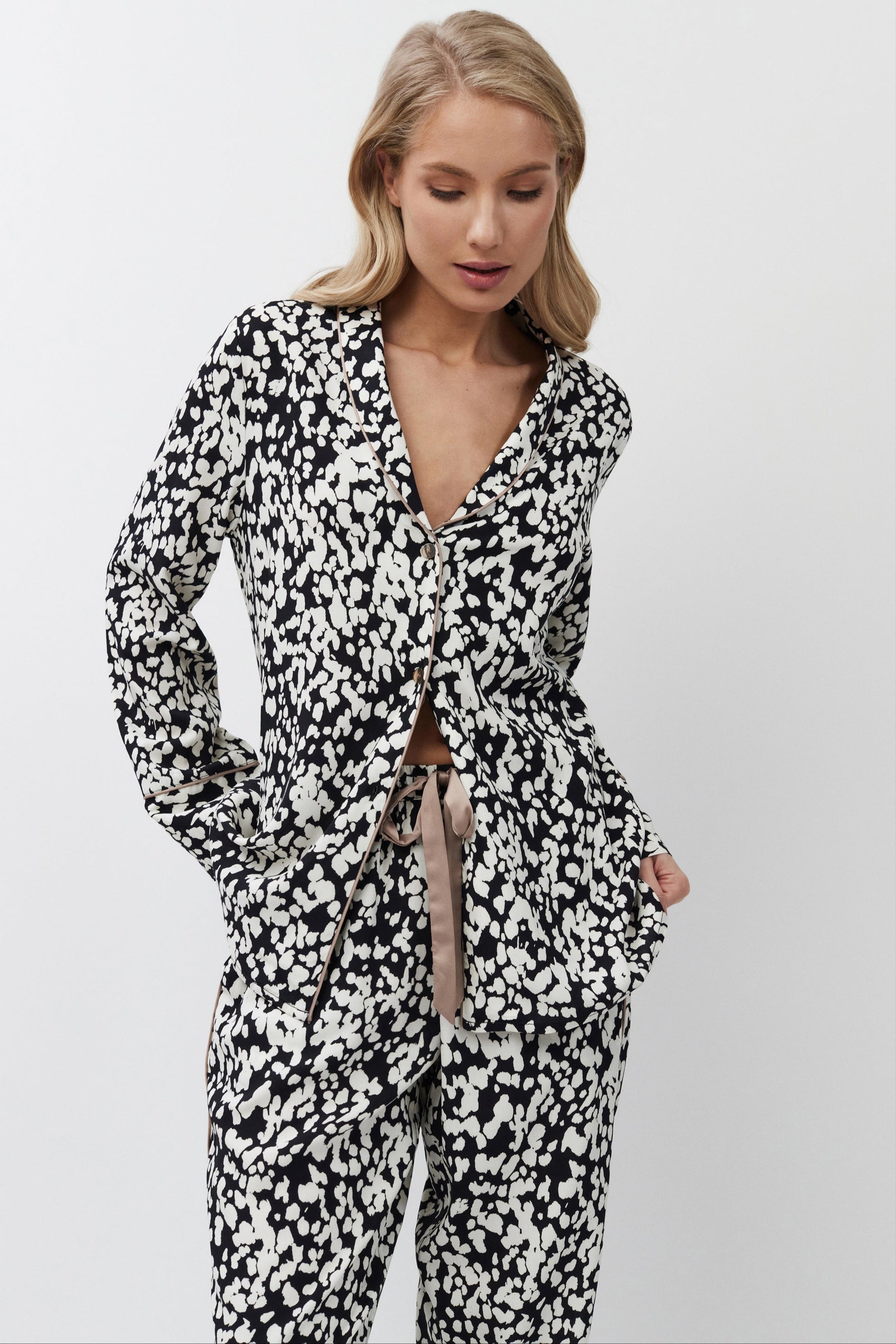 Woman wearing a black and white patterned pajama set on a plain background