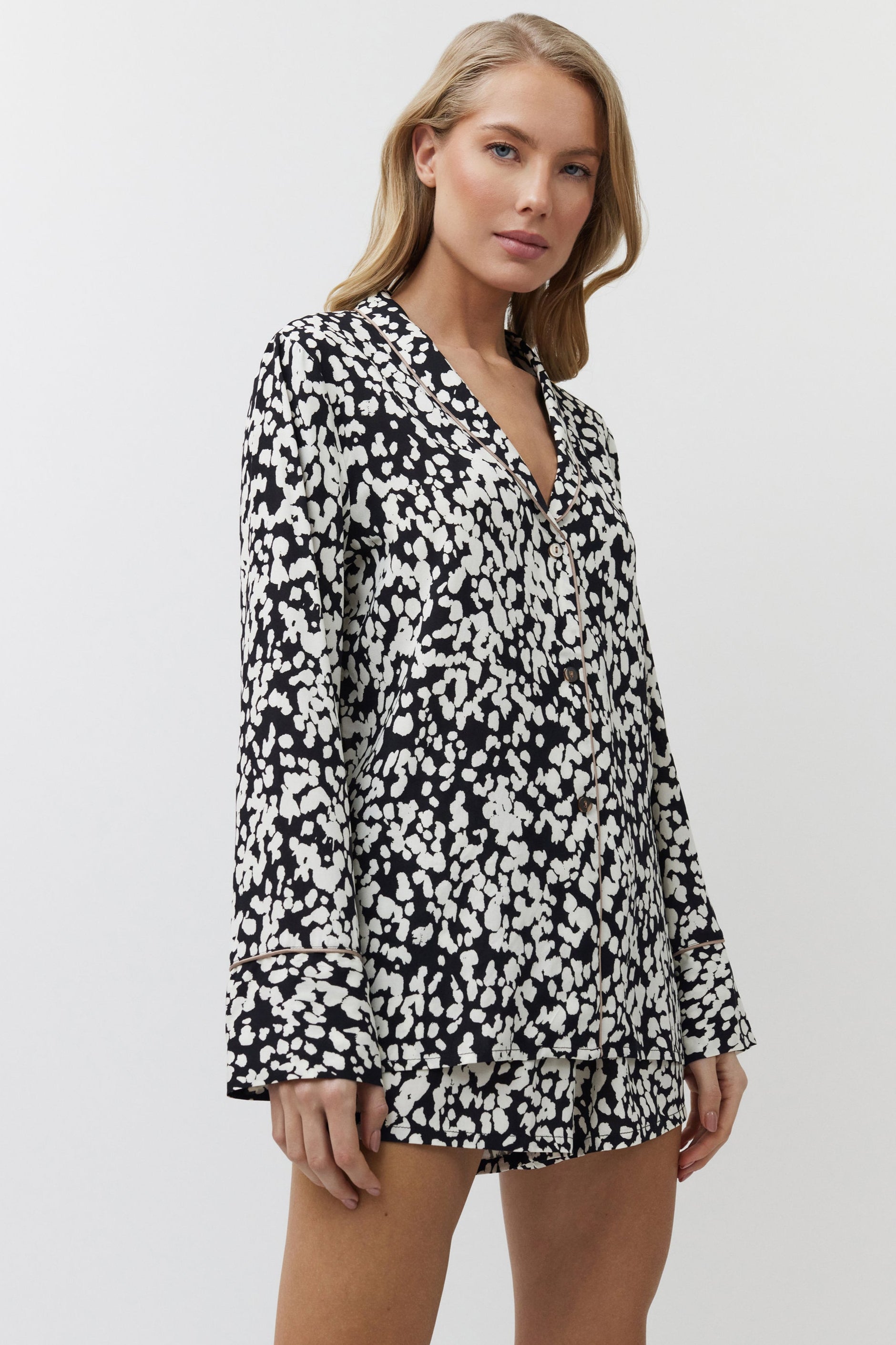 Woman wearing a black and white patterned pajama set on a plain background