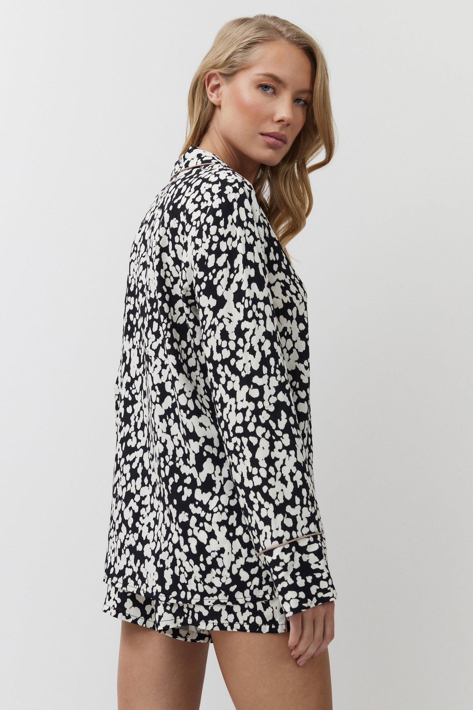 Woman wearing a black and white patterned pajama set on a plain background