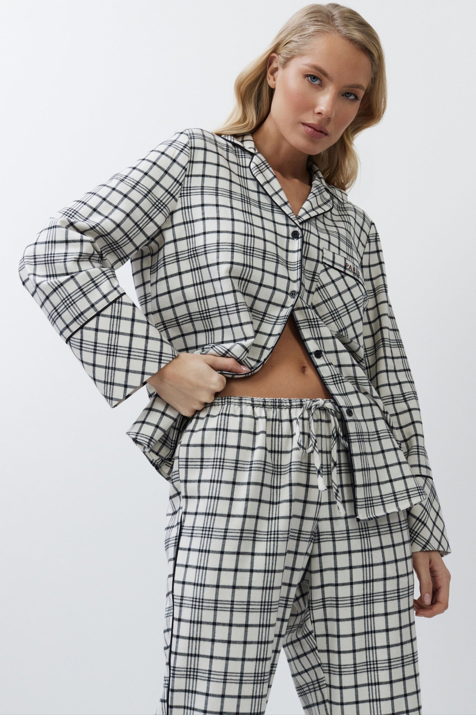 Woman wearing a black and white checkered pajama set on a plain background