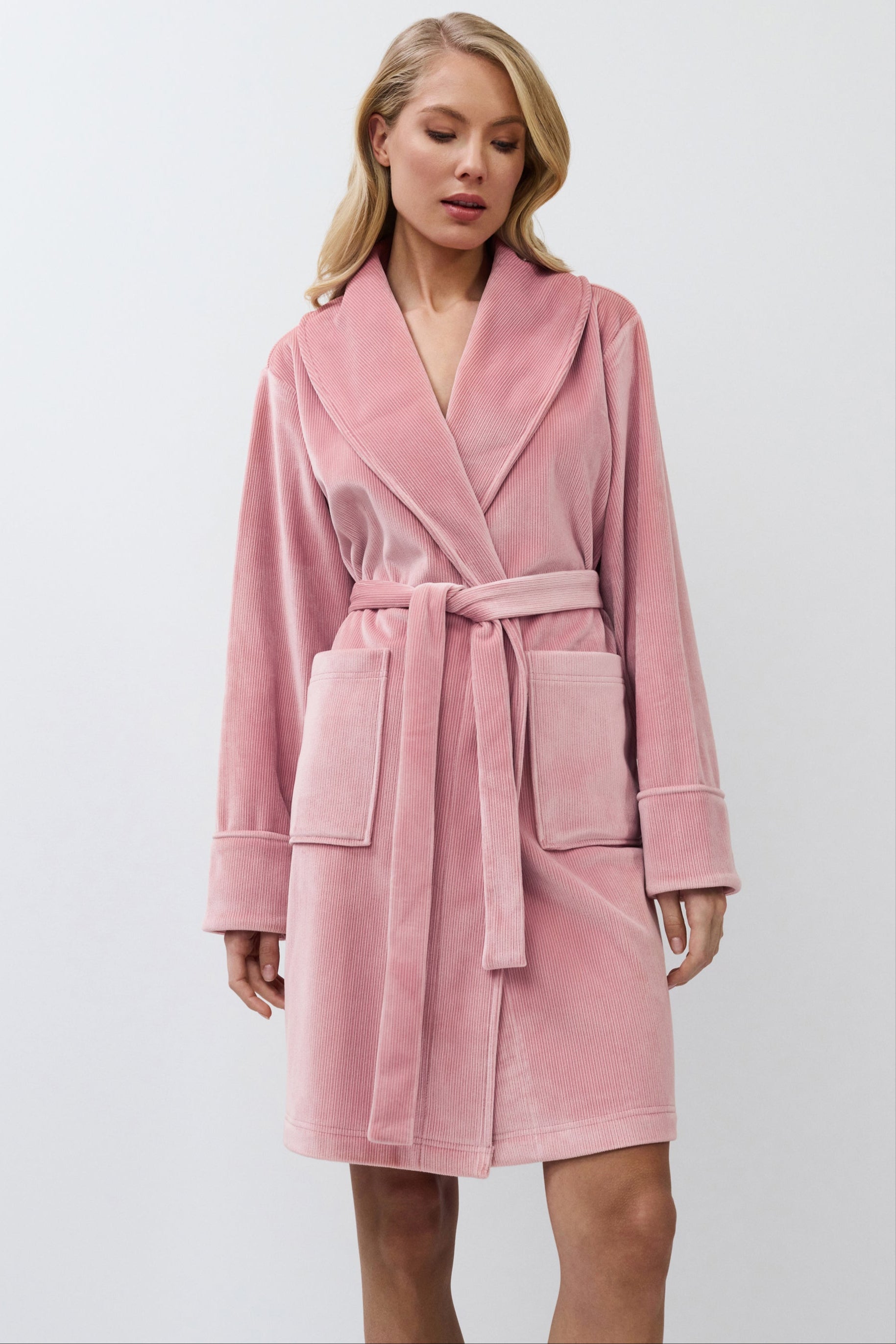Woman wearing a pink bathrobe against a white background
