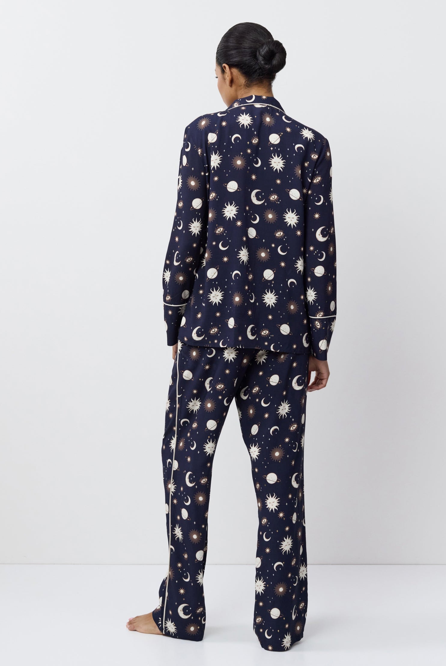 Person wearing a navy blue pajama set with pattern on a white background