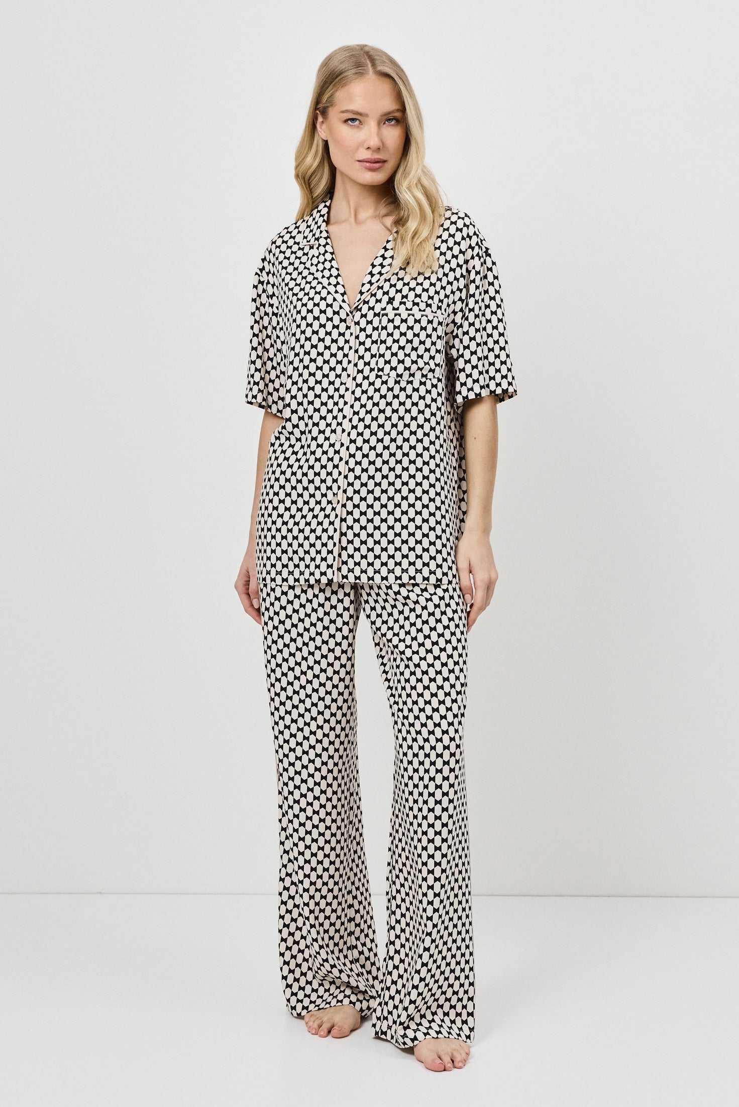 Woman wearing a patterned pajama set on a white background.