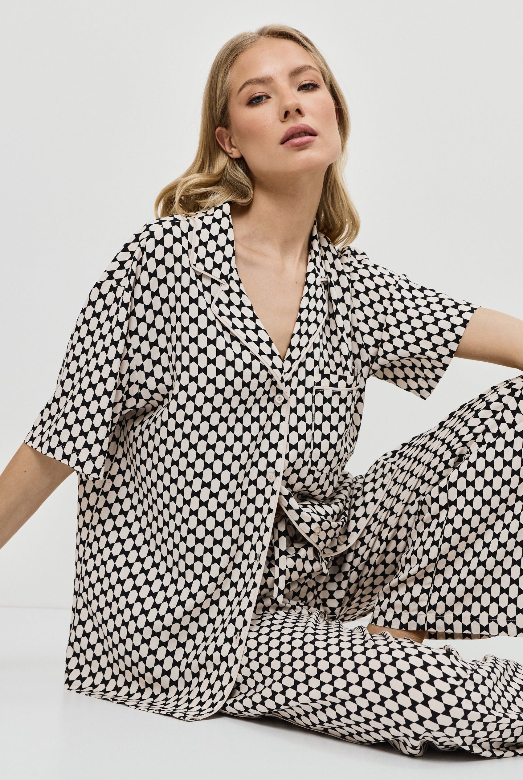 Woman wearing a patterned pajama set on a plain background