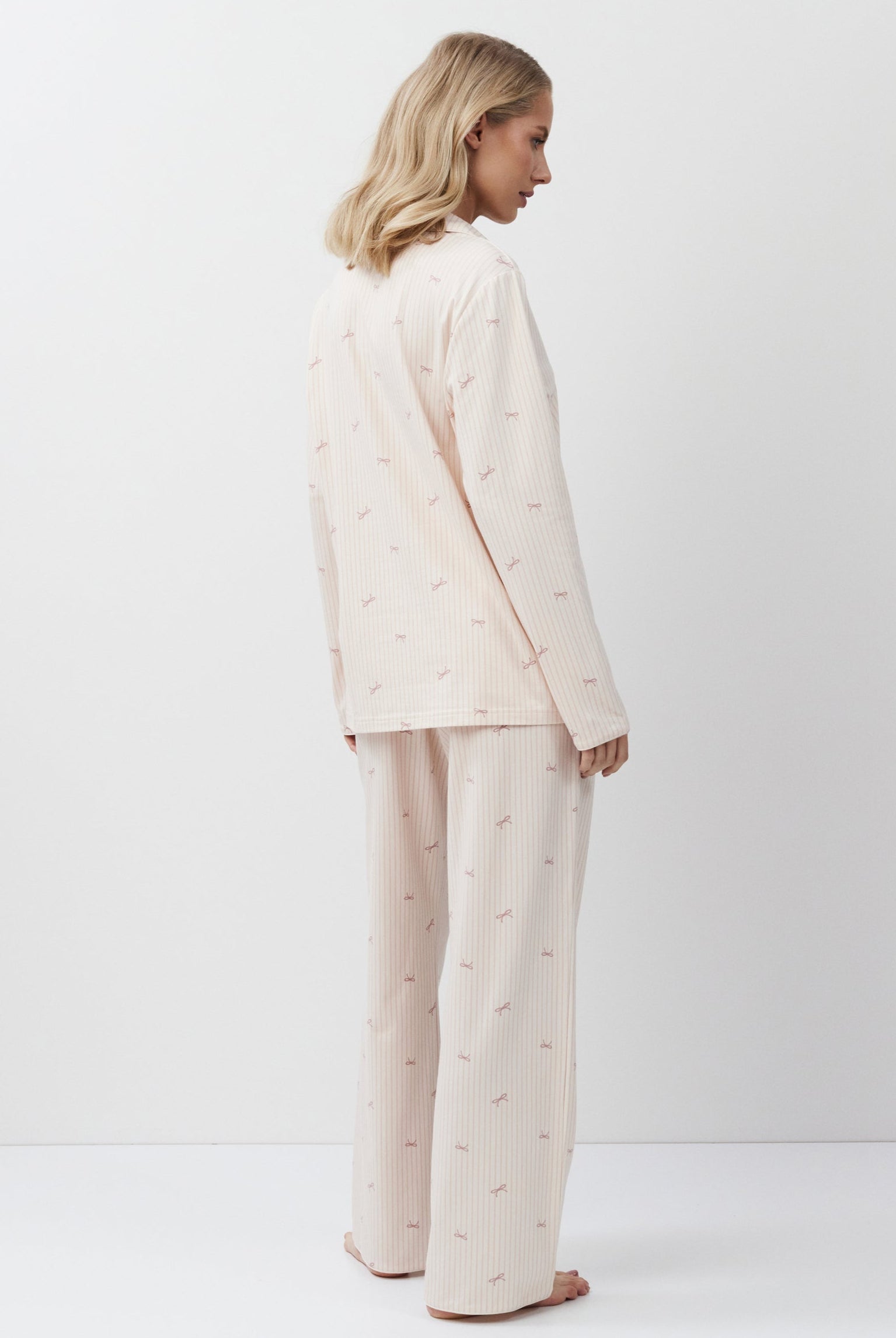 Woman wearing a pink-colored pajama set on a white background