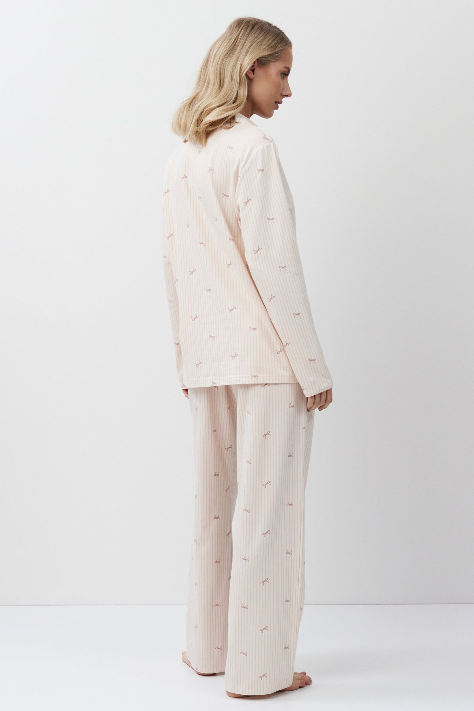 Woman wearing a pink-colored pajama set on a white background