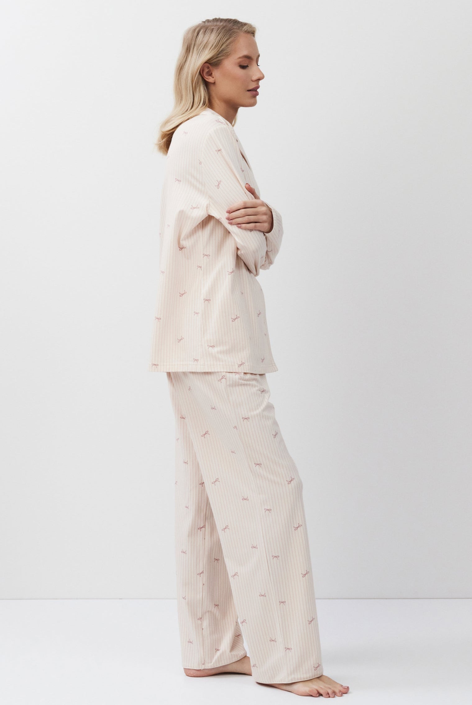 Woman wearing a pink-colored pajama set against a white background