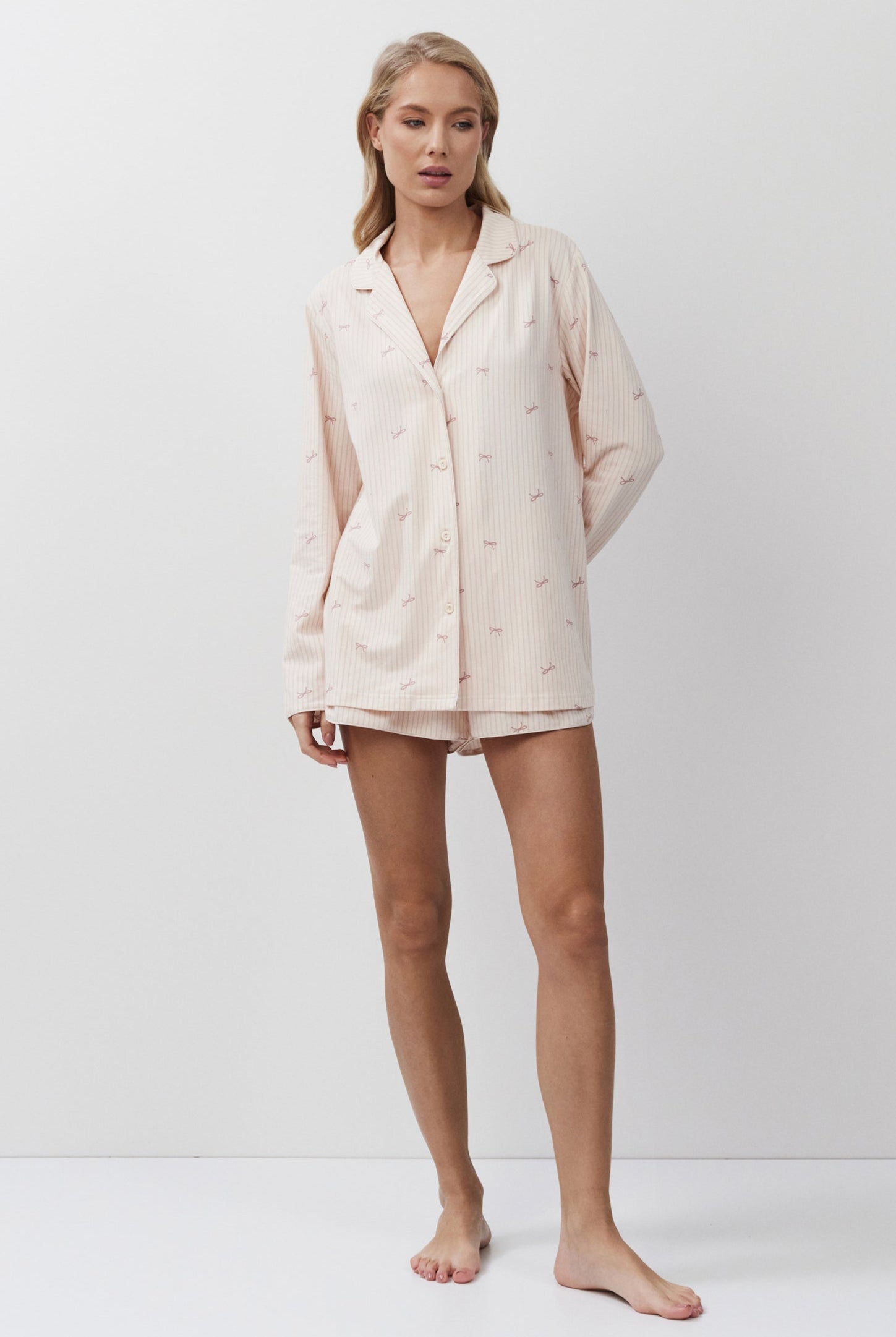 Woman wearing a pijnk pajama set against a white background