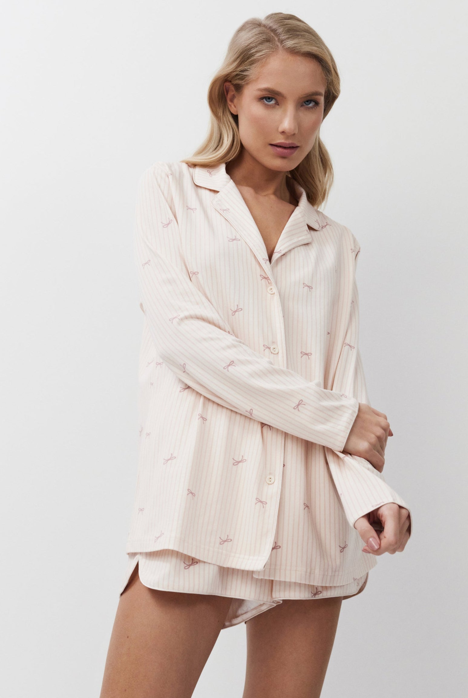 Woman wearing a light pink pajama set against a white background