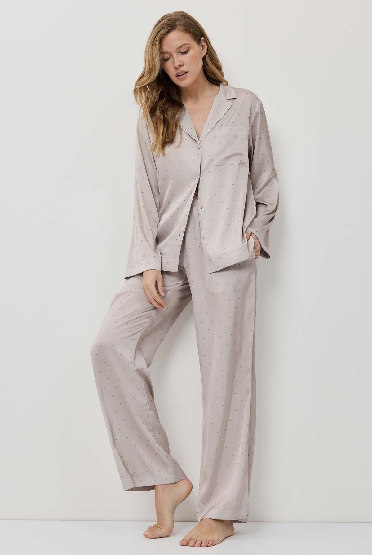 Woman wearing a beige pajama set against a white background