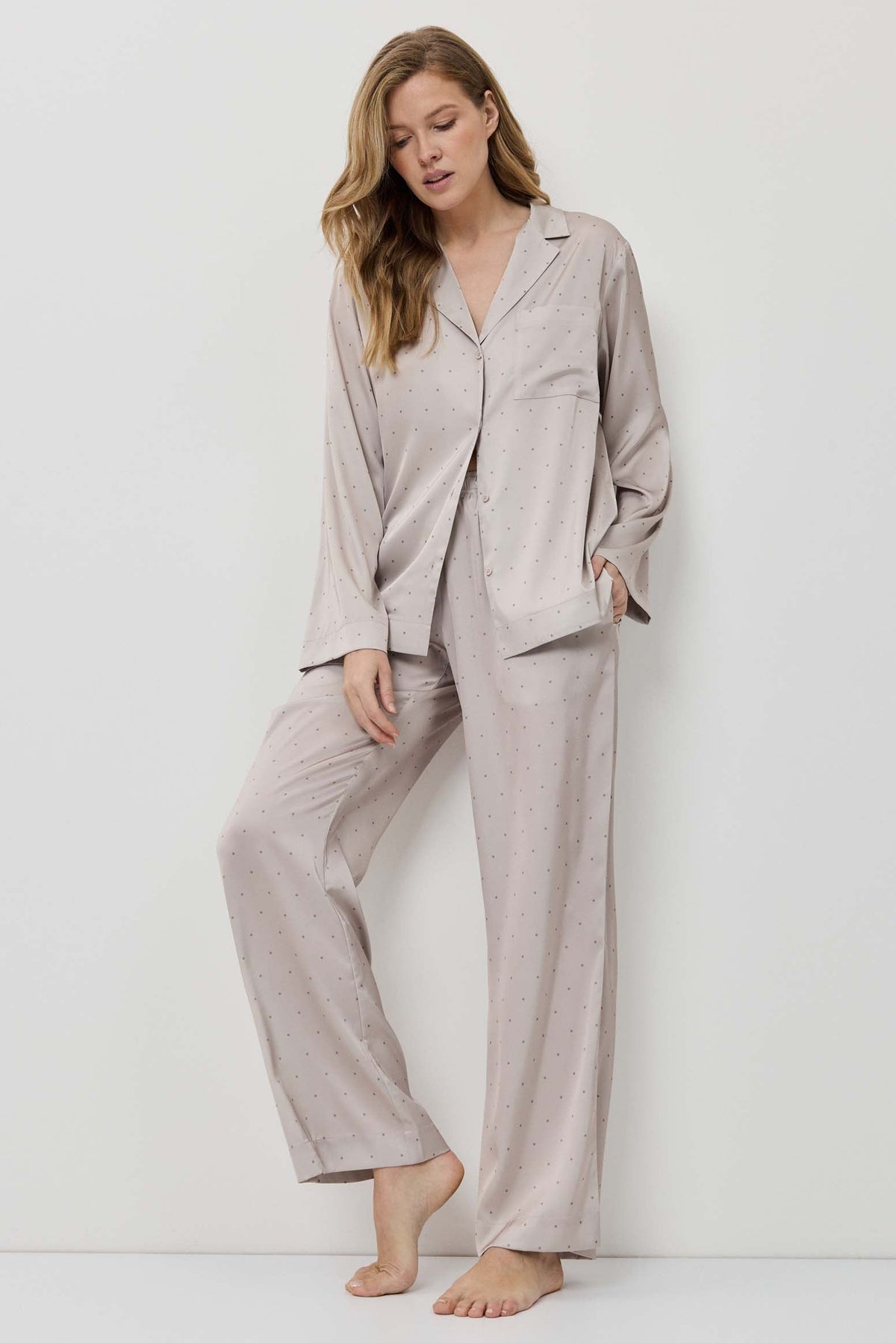 Woman wearing a beige pajama set against a white background