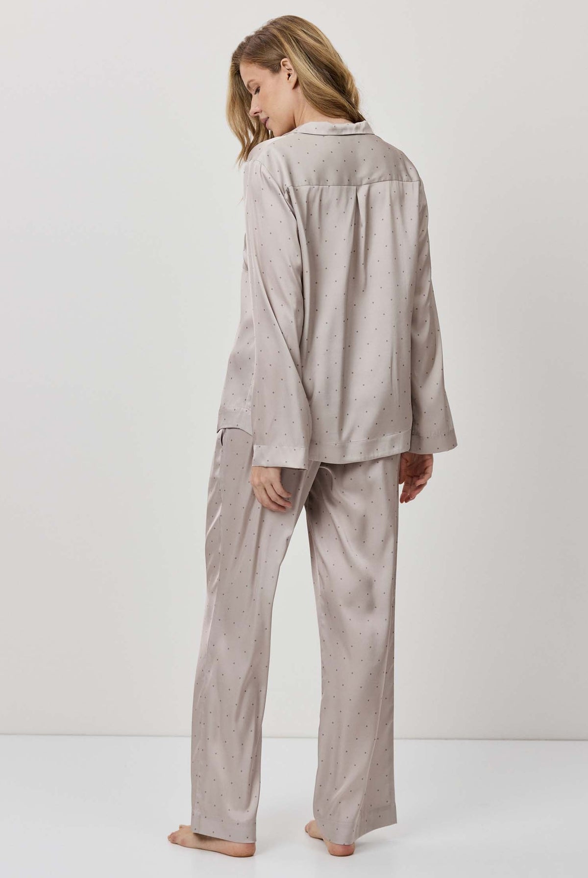 Person wearing a beige pajama set against a white background