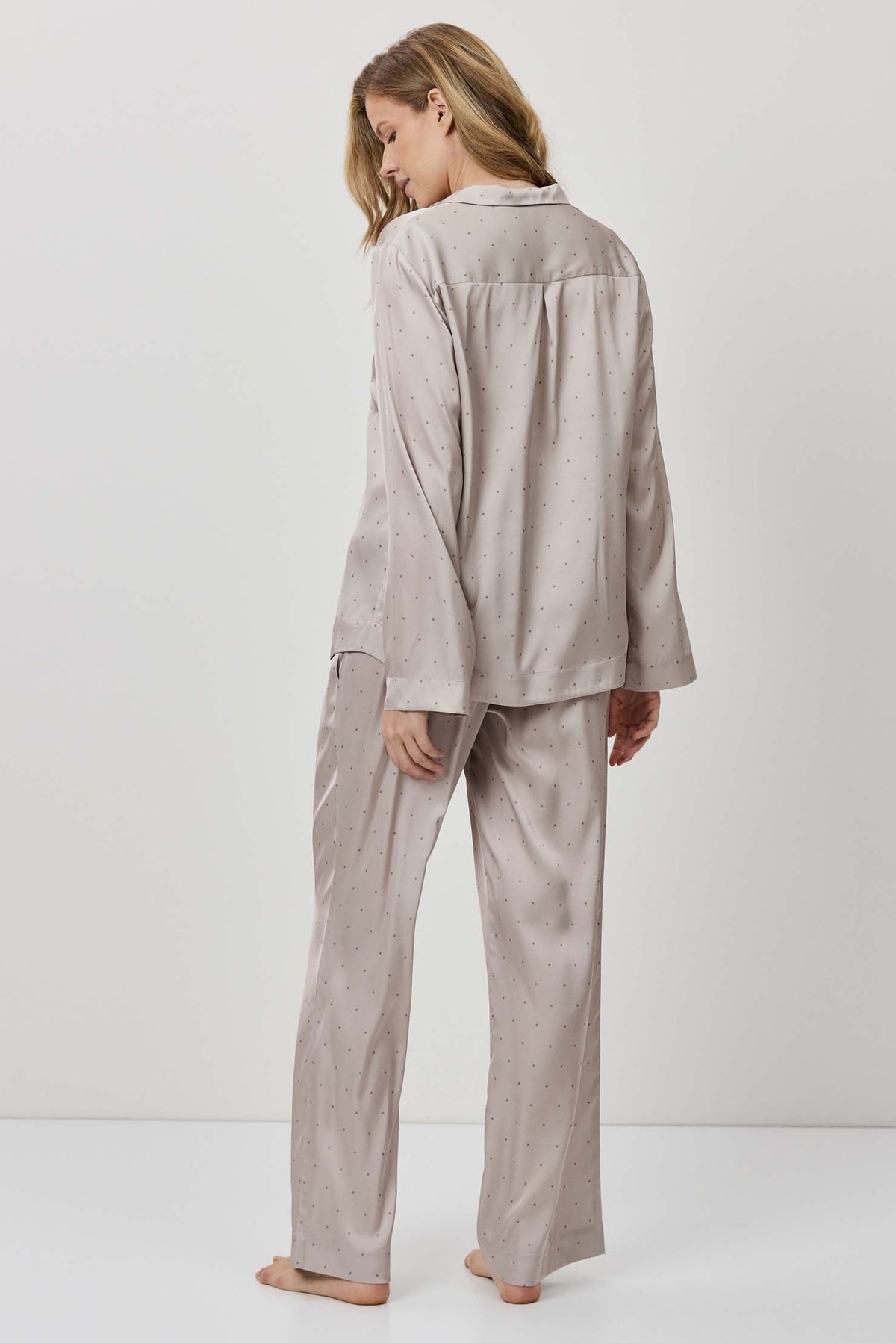 Person wearing a beige pajama set against a white background