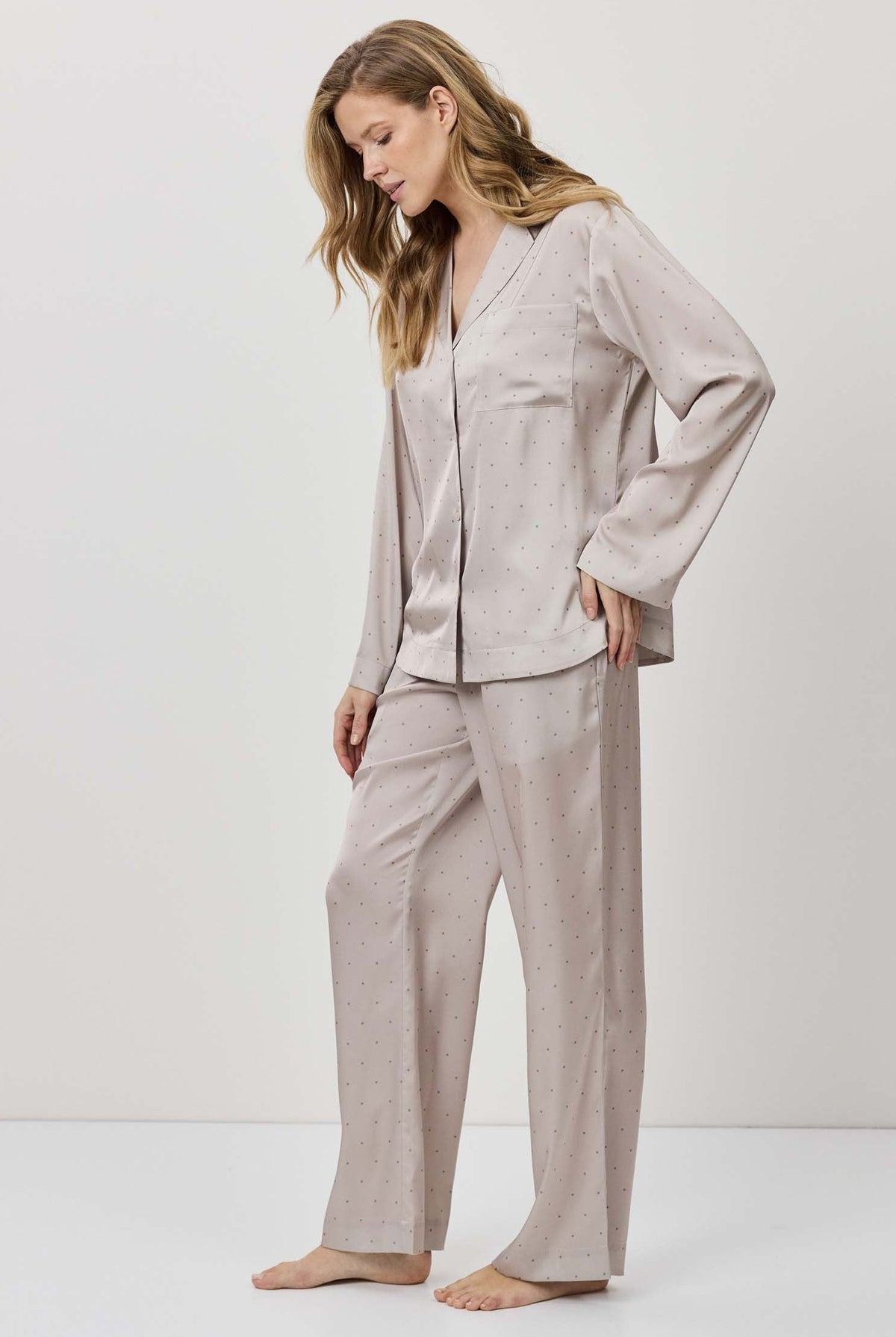 Woman wearing a light gray pajama set against a white background