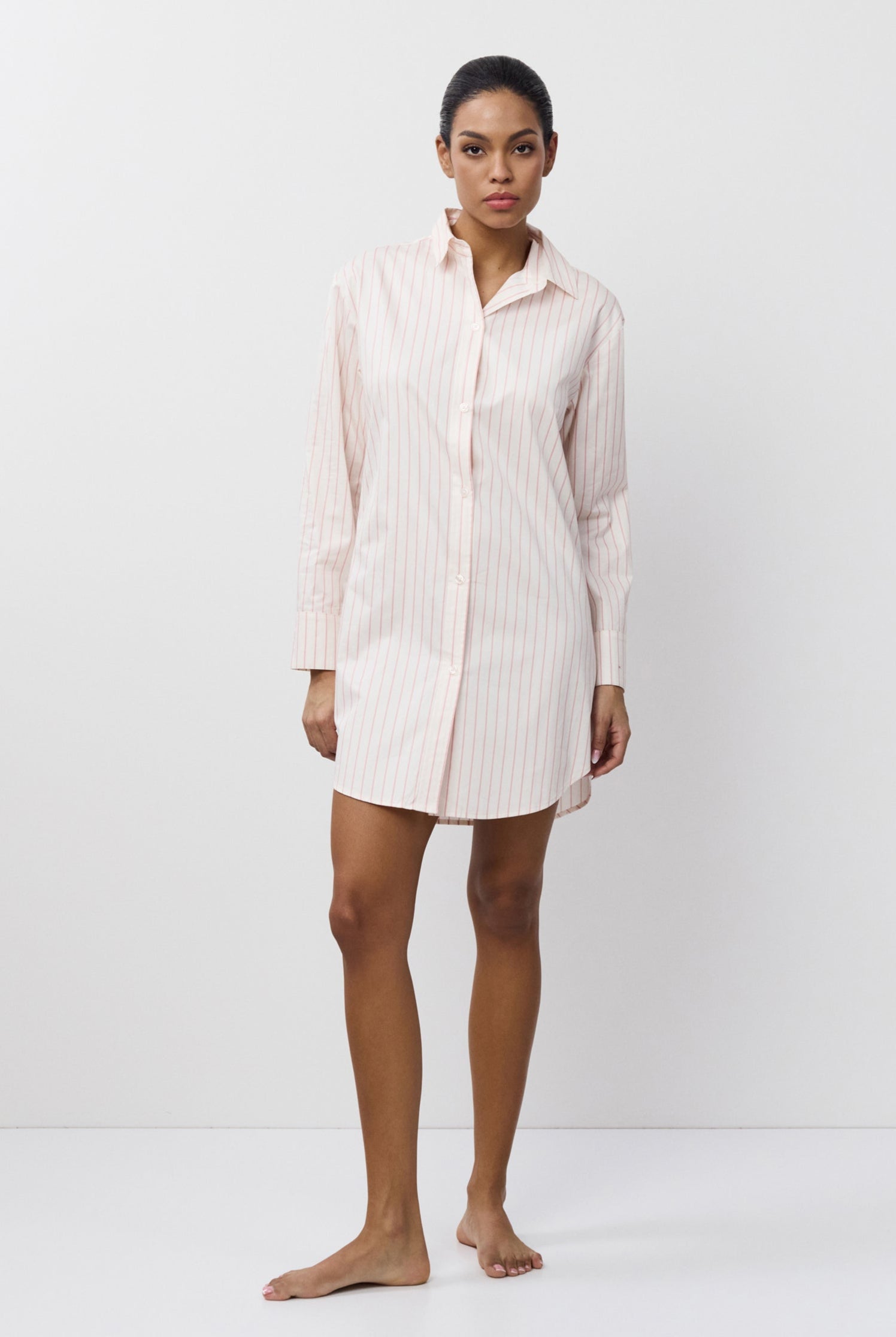 Woman wearing a light-colored shirt nightdress against a white background