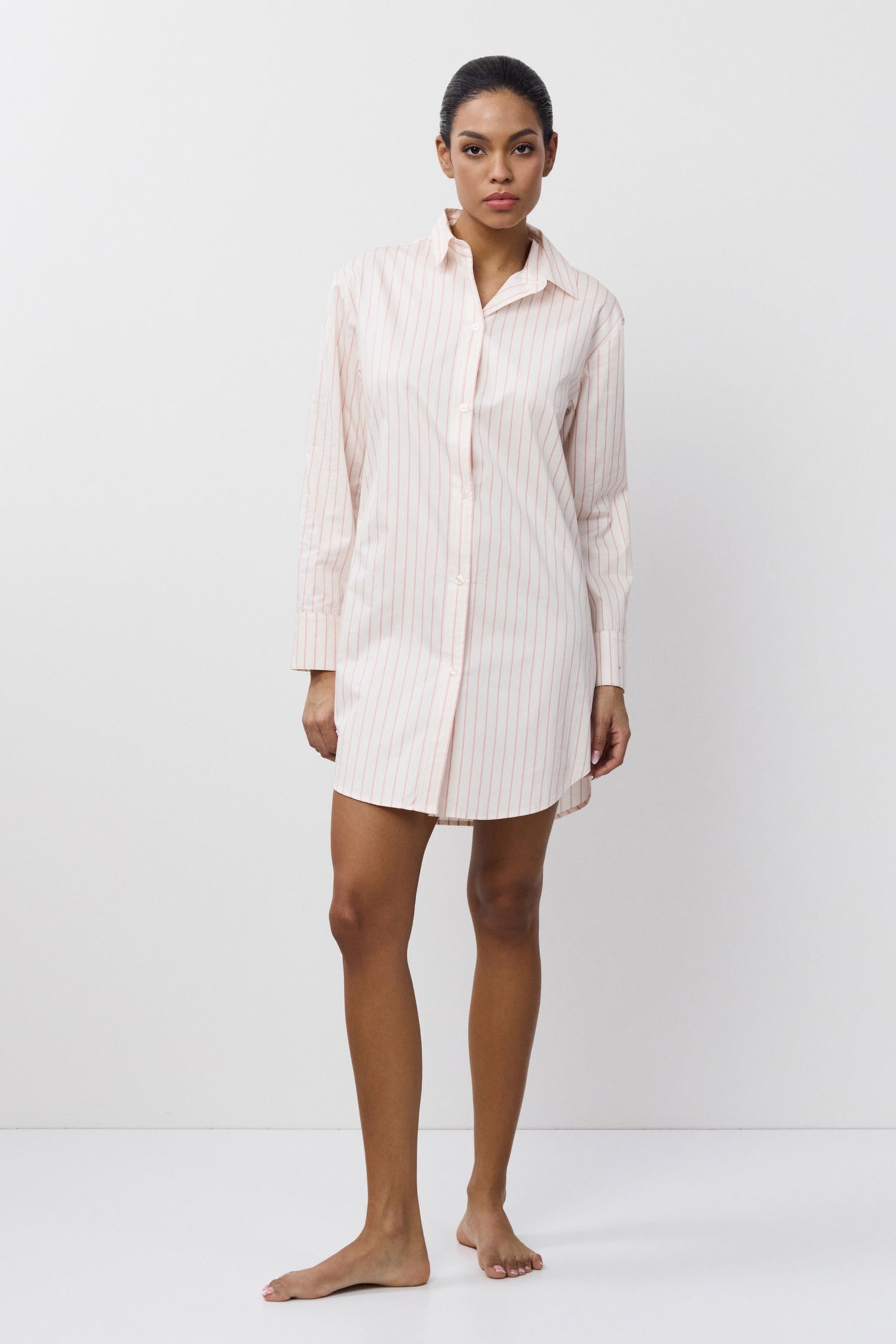 Woman wearing a light-colored shirt nightdress against a white background