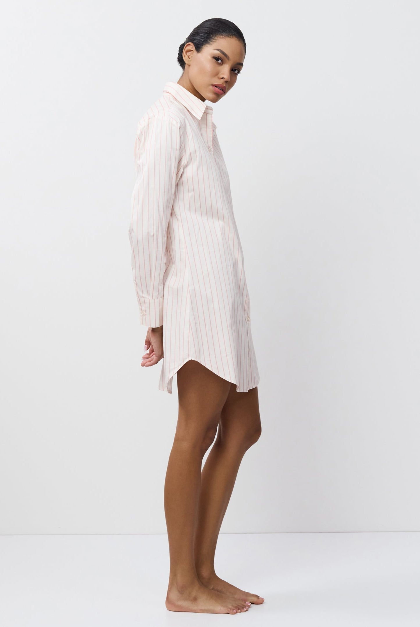 Woman wearing a white stripped nightdress against a white background