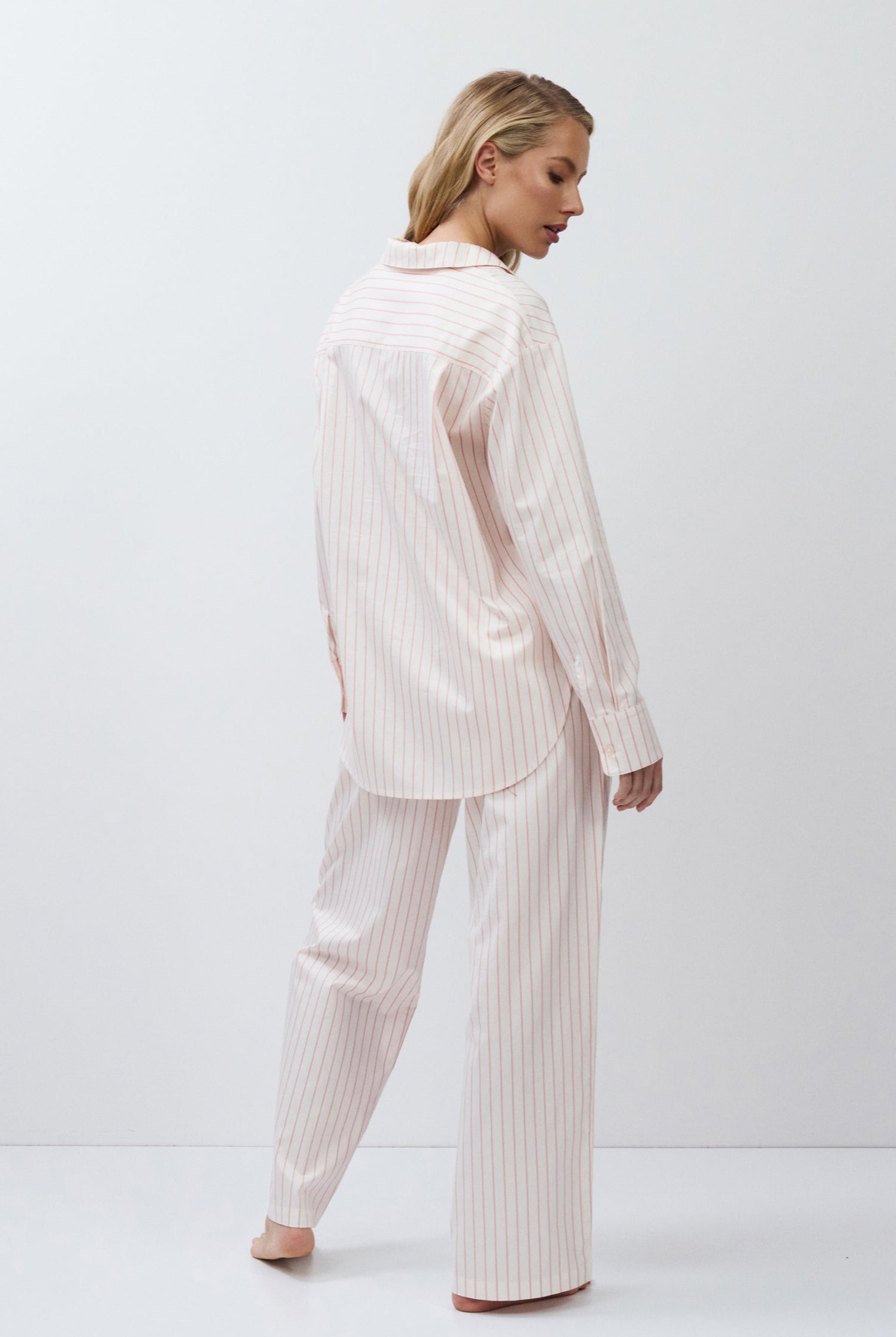 Woman wearing a light pink pajama set against a white background